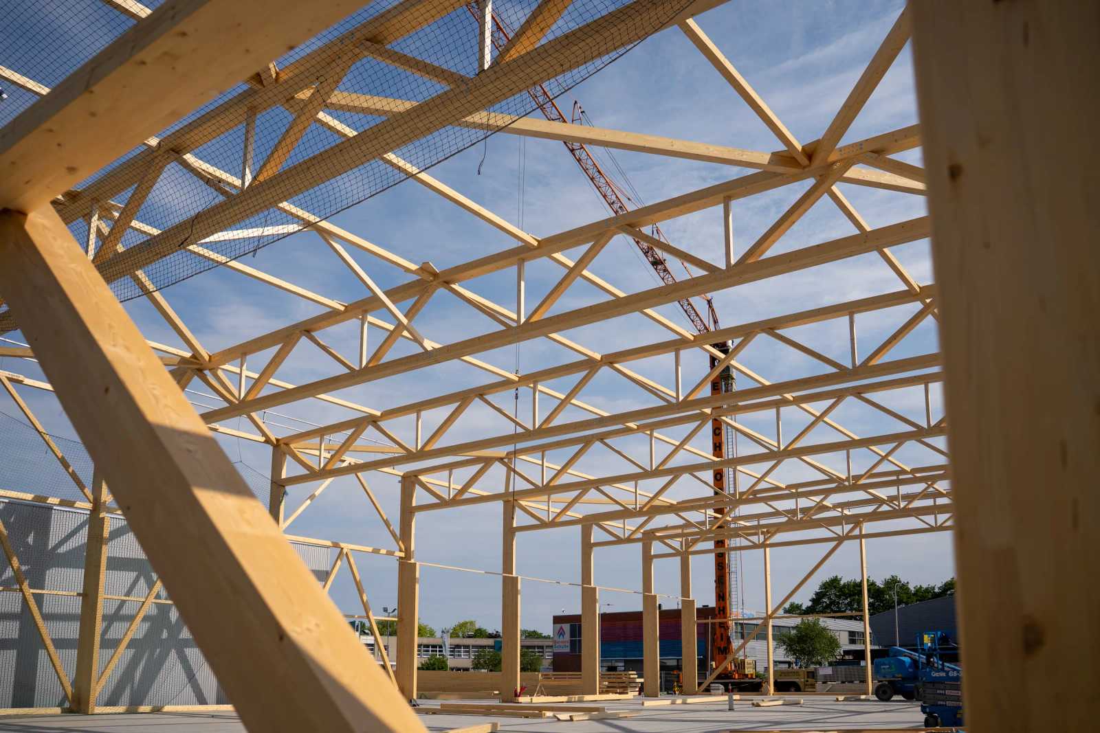 Errichtung der Holz-Fachwerkbinder einer Halle, Blick ins Tragwerk mit Kran