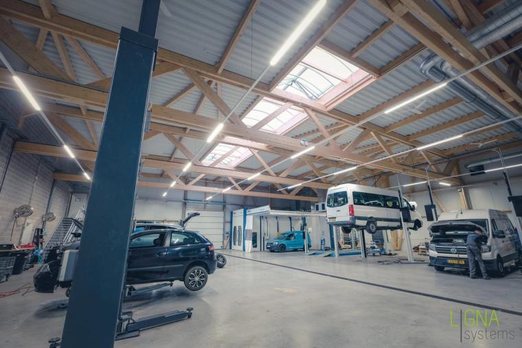 Kfz-Werkstatt mit Hebebühnen und Transportern unter dem sichtbaren Holzdachtragwerk