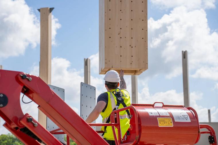 Monteur auf der Hebebühne arbeitet an einer aufgerichteten Holz-Rohrstütze