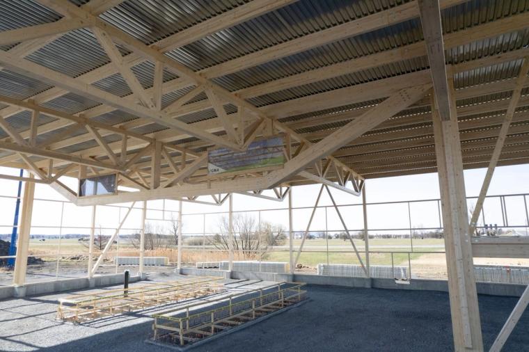 Intérieur sous la charpente terminée en lamellé-collé, avec vue sur le rez-de-chaussée ouvert