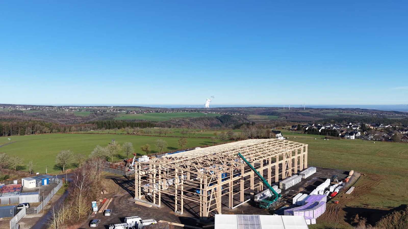 Timber hall under construction in the landscape, aerial view