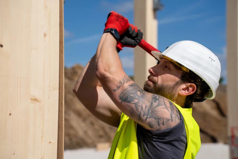 Monteur arbeitet am Fuß einer Holz-Rohrstütze
