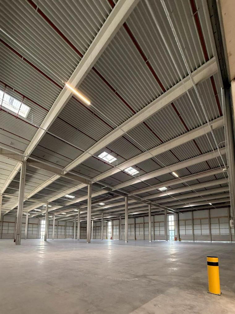 Innenansicht eines Hallenschiffs mit Stahlkonstruktion im Dachtragwerk, leerem Grundriss und Betonboden.