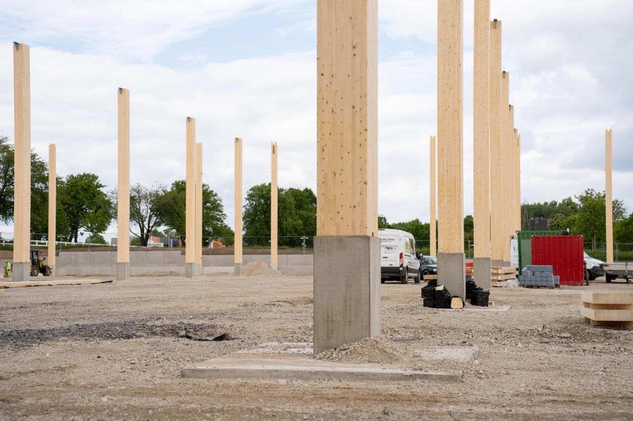 Veld van slanke houten kolommen op betonsokkels tijdens de montage van een hal