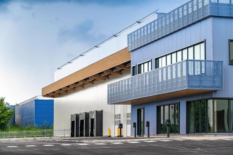 Fassadendetail mit holzverkleidetem Vordach und perforierter Metallbrüstung über den Verladetoren