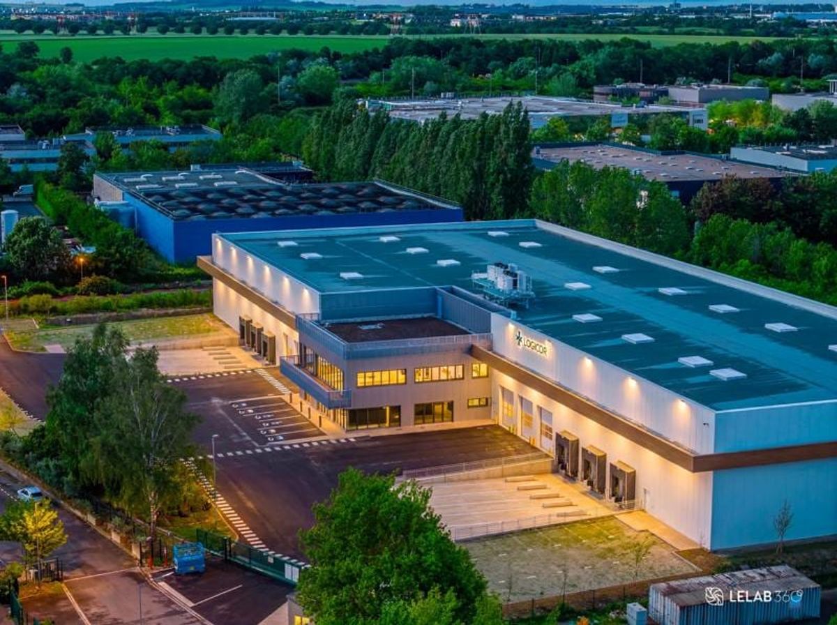 Abendliche Luftaufnahme des beleuchteten Logistikzentrums im Gewerbegebiet