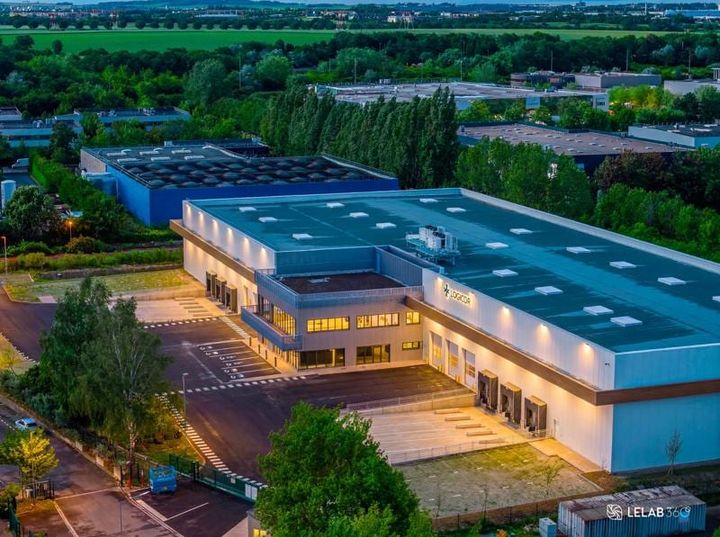 Abendliche Luftaufnahme des beleuchteten Logistikzentrums im Gewerbegebiet