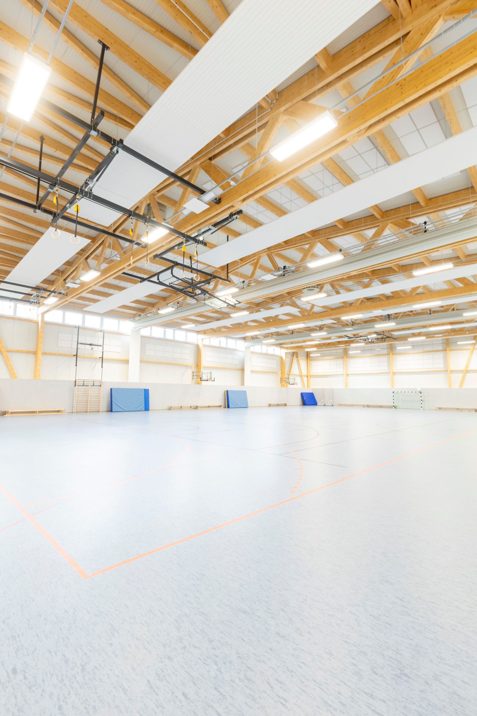 Sports hall with wide-span timber roof structure and exposed glulam trusses