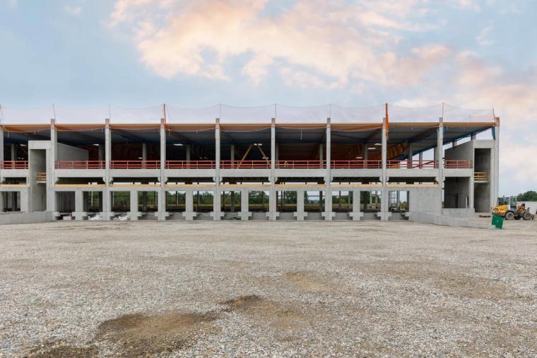 Long elevation of the shell, two-storey concrete frame with the timber roof structure beneath protective netting