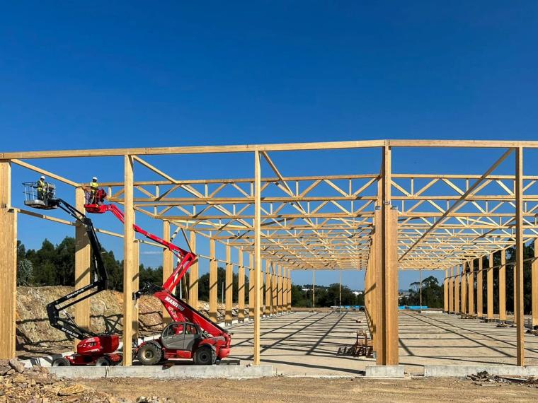 Symmetrische Innenansicht von der Giebelseite mit aufgereihten Fachwerkbindern und Holzstützen