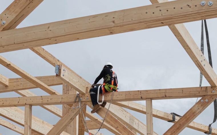 Monteur im Dachtragwerk zwischen Fachwerkträgern