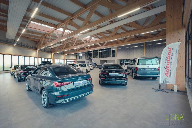Showroom mit ausgestellten Fahrzeugen und Lux-Autoland-Banner unter der Holzdachkonstruktion
