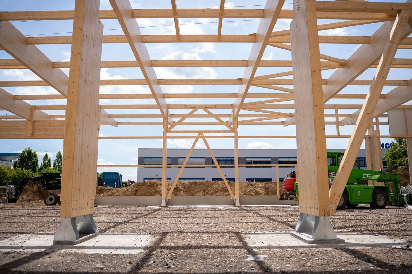 Erected timber structure of a system hall on site against a blue sky