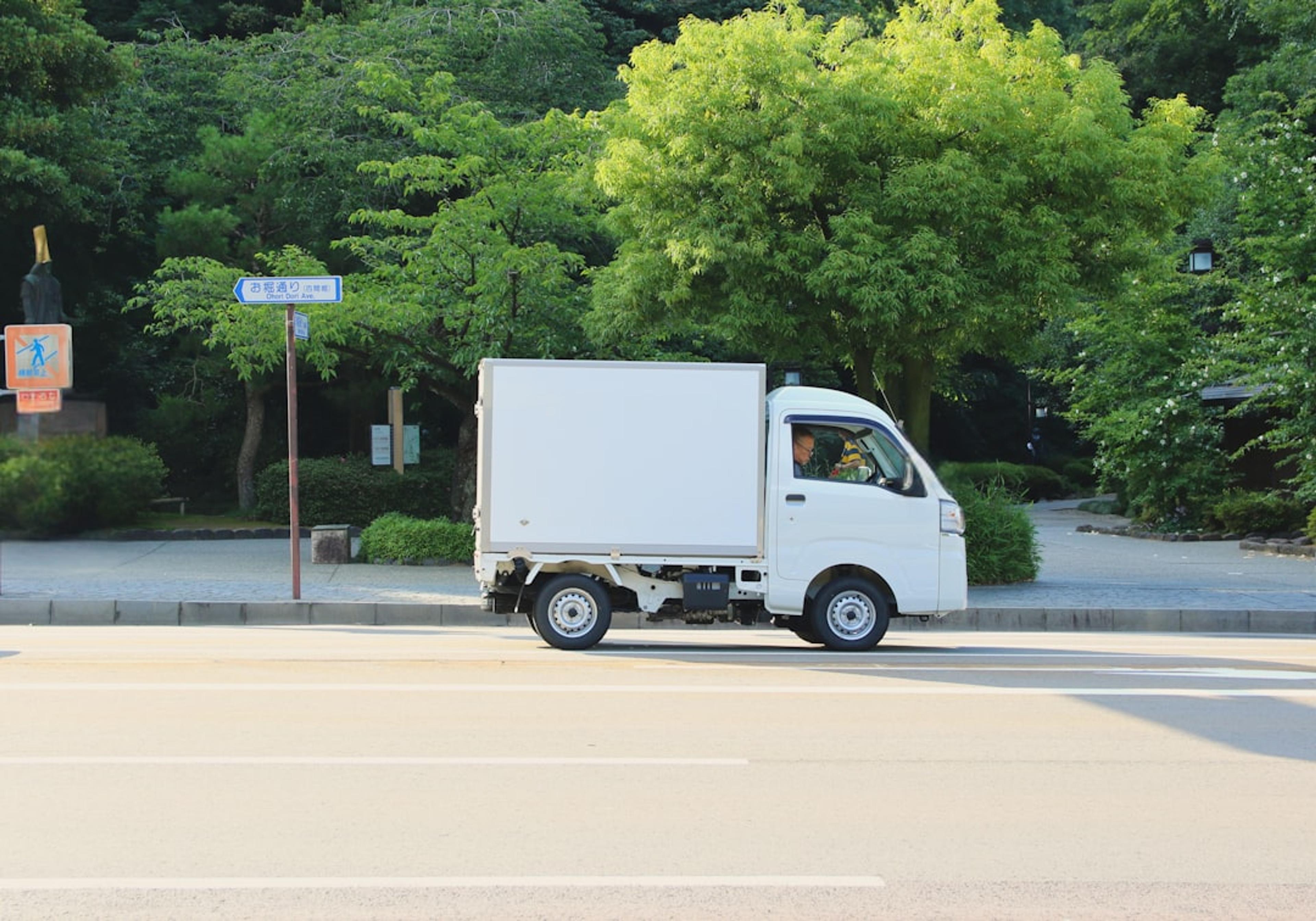 A white delivery truck driving down a street