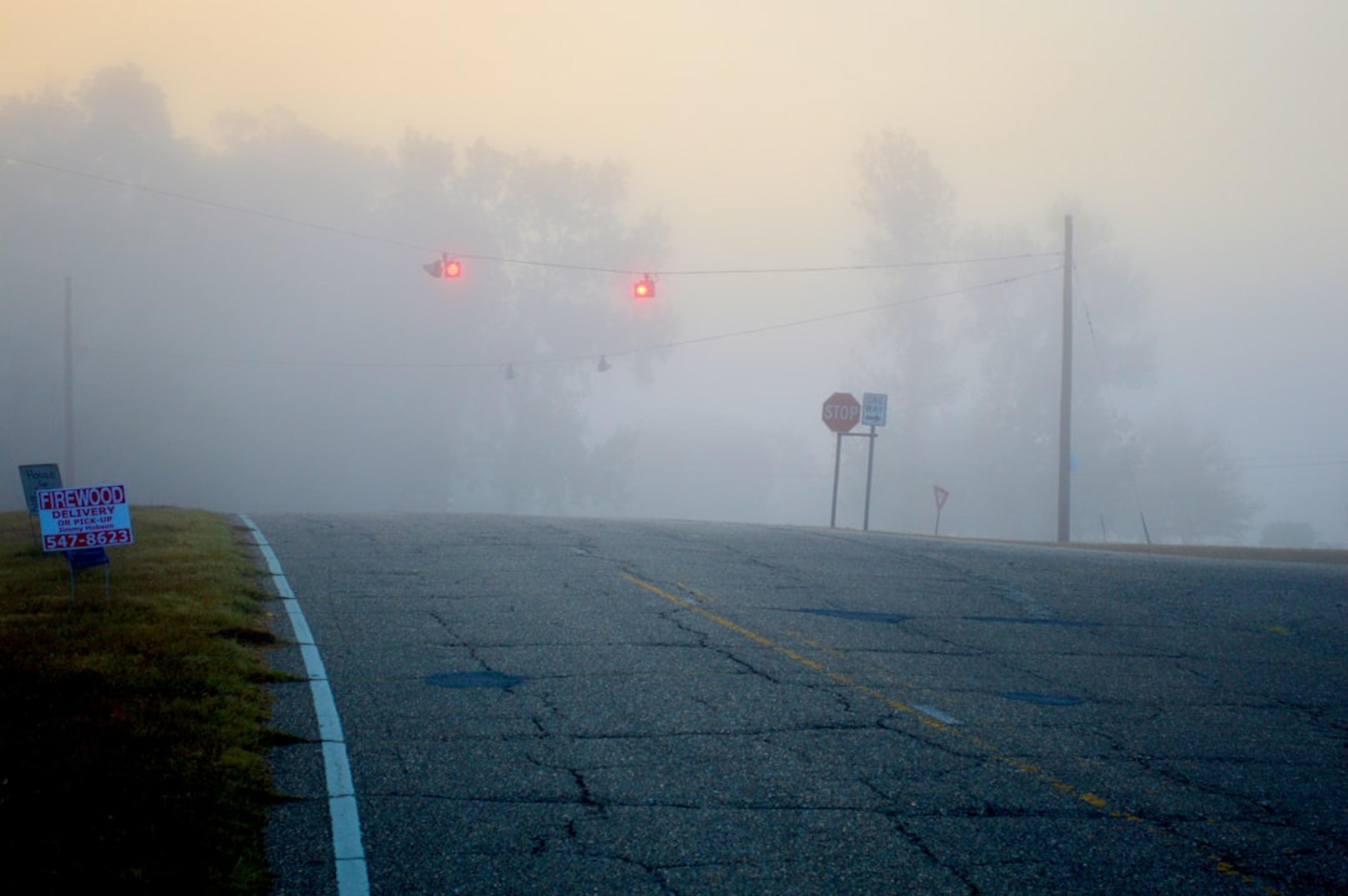 Traffic lights glowing through thick morning fog.