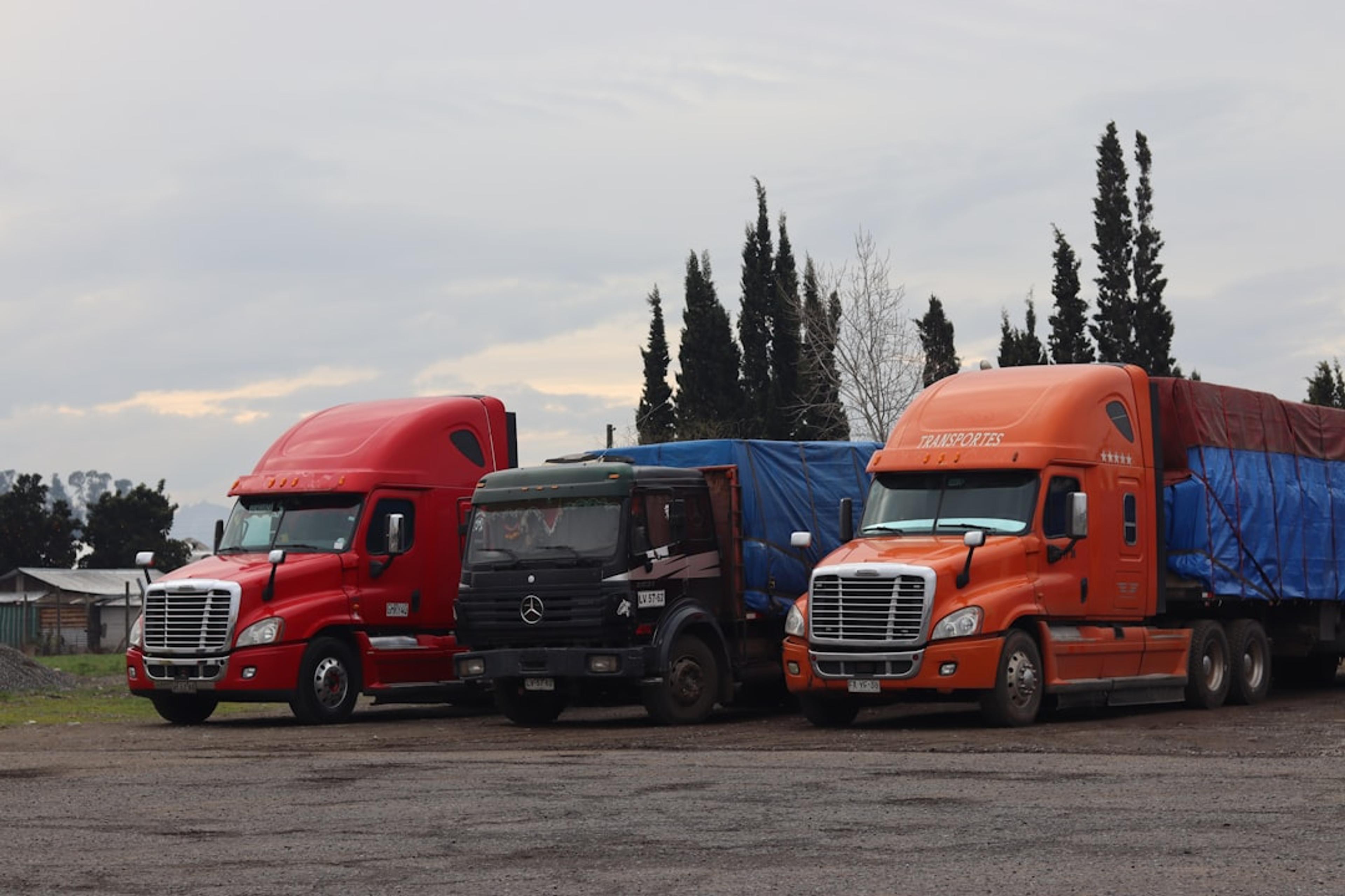 Three trucks are parked in a lot.