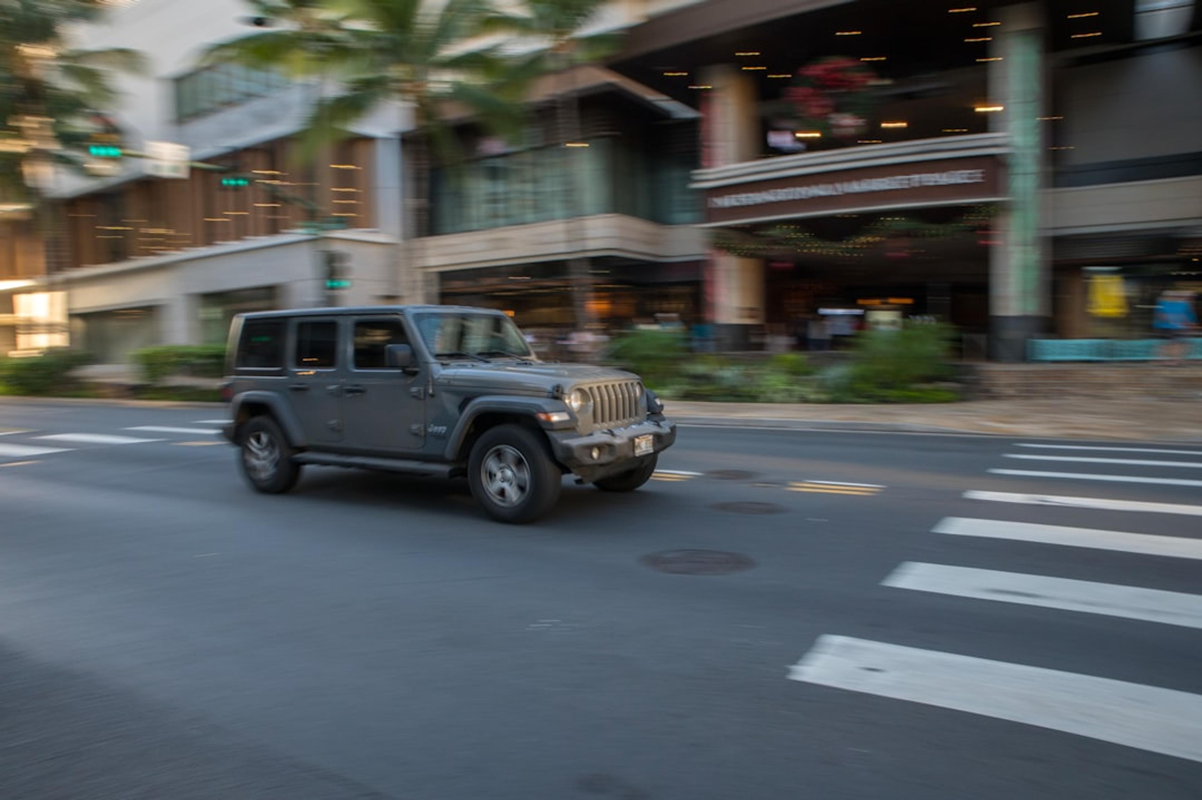 Gray jeep driving on a city street