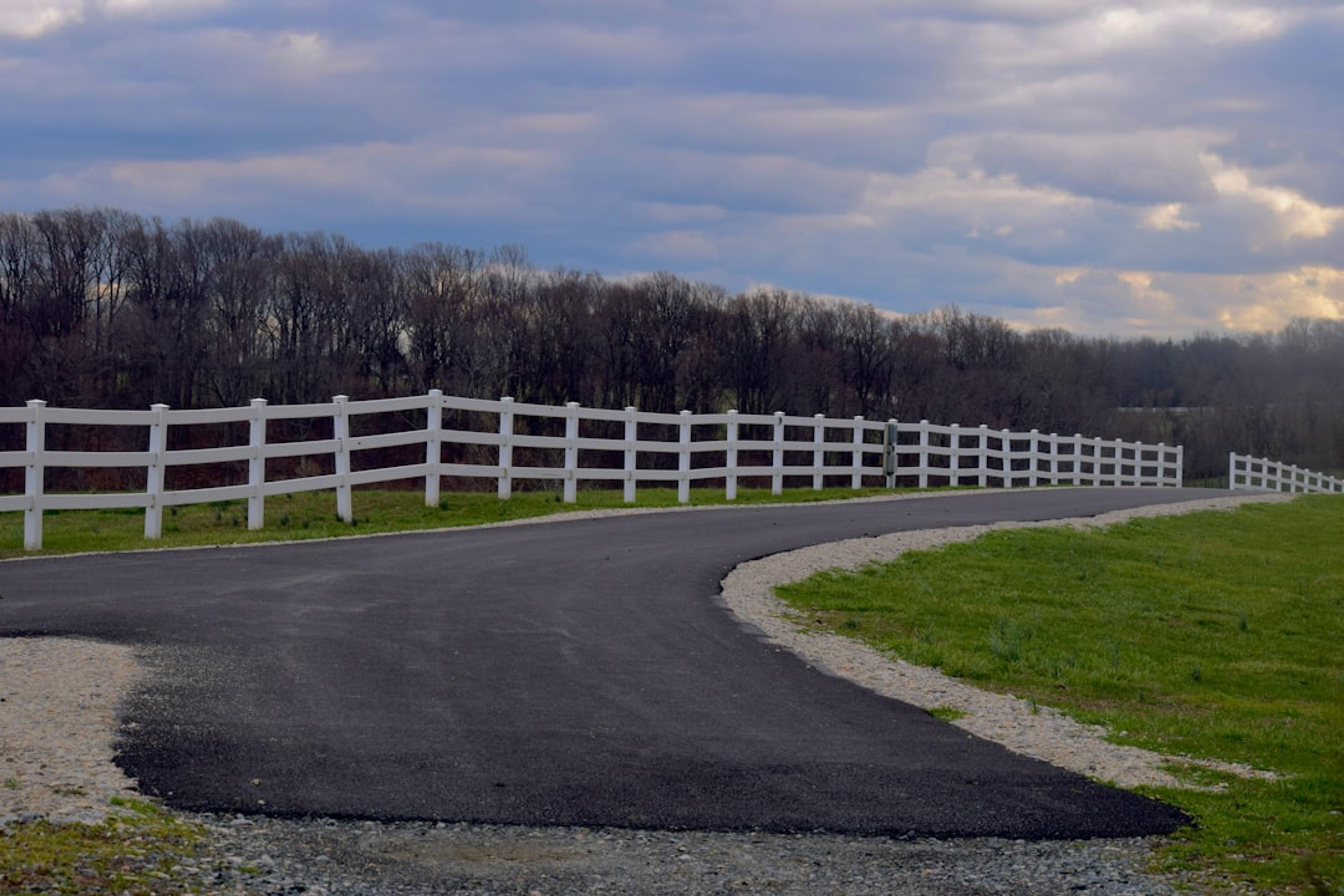 a road with white fences and grass