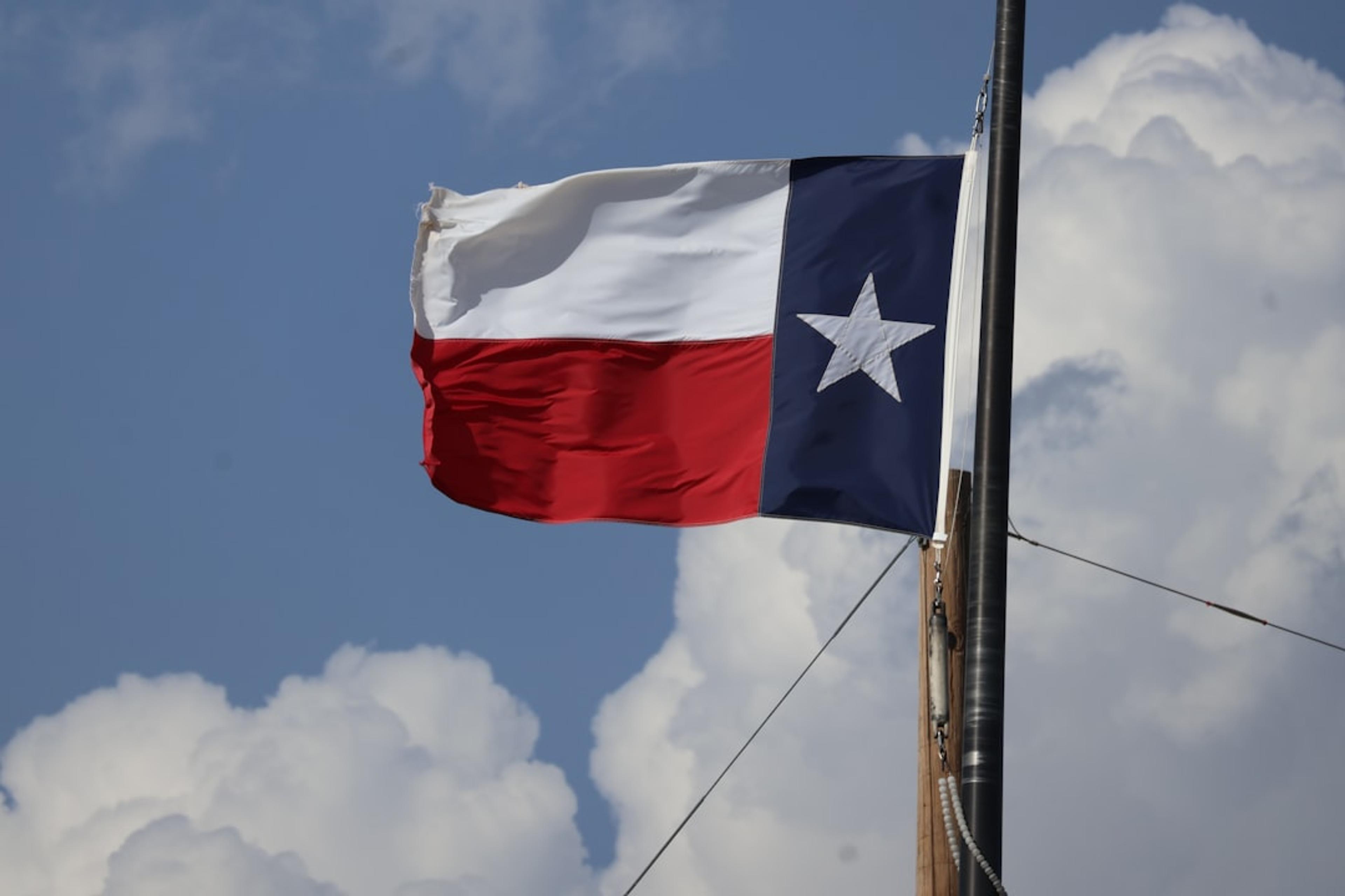 The texas flag flies proudly in the sky.