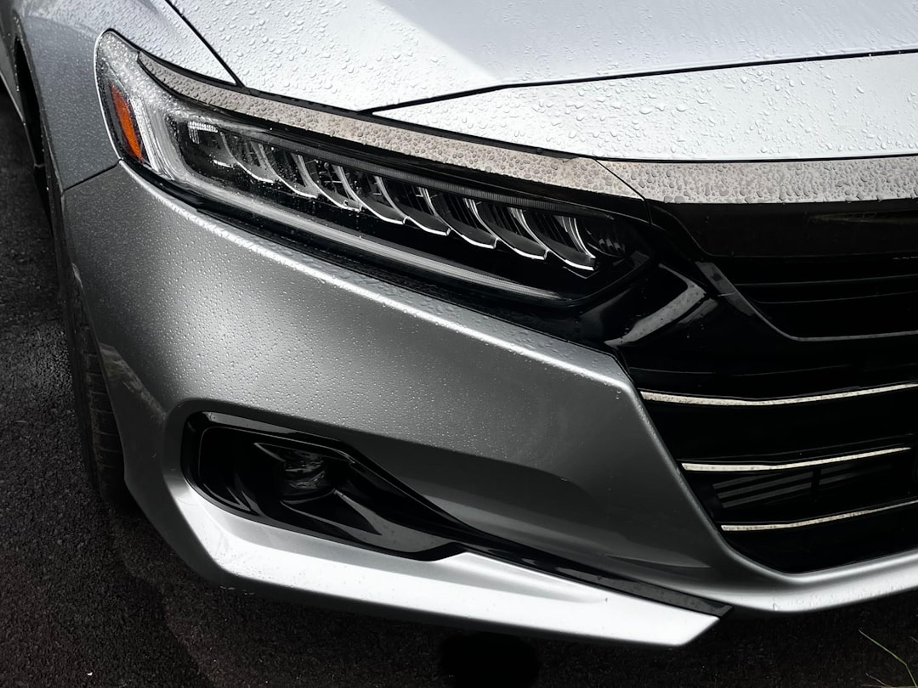Close-up of a silver car's headlight and grille