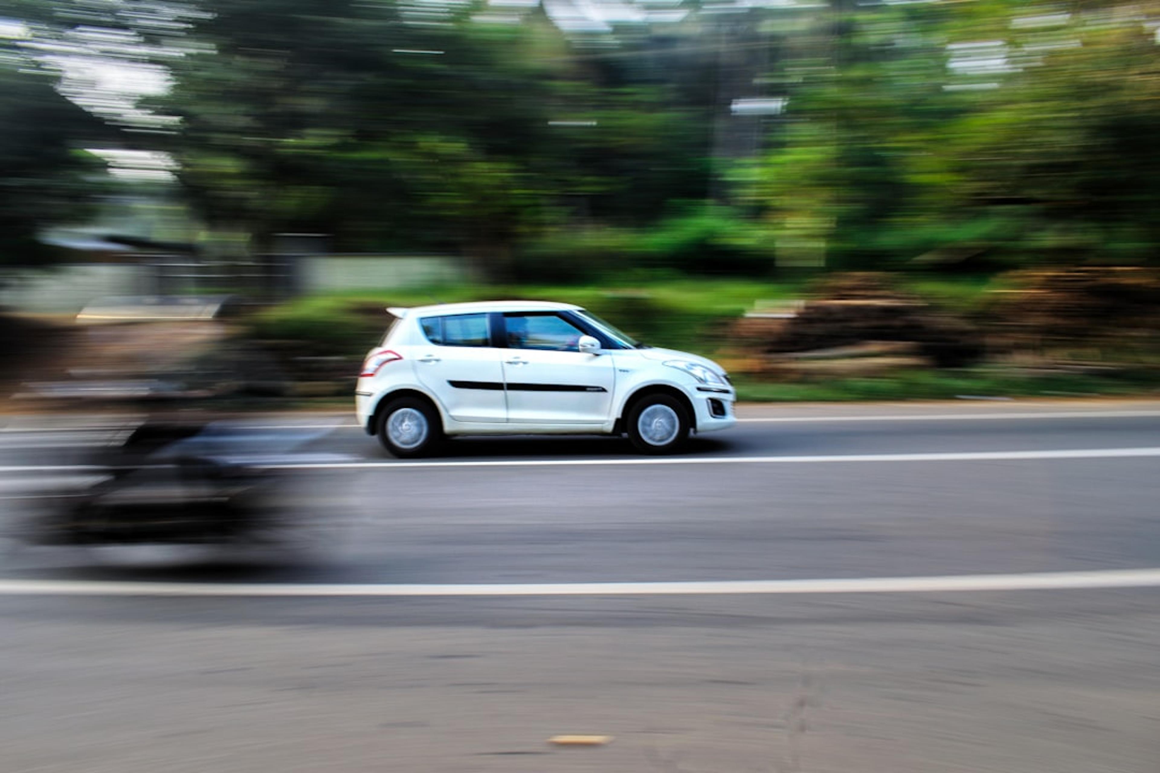 a white car driving down a street next to a forest