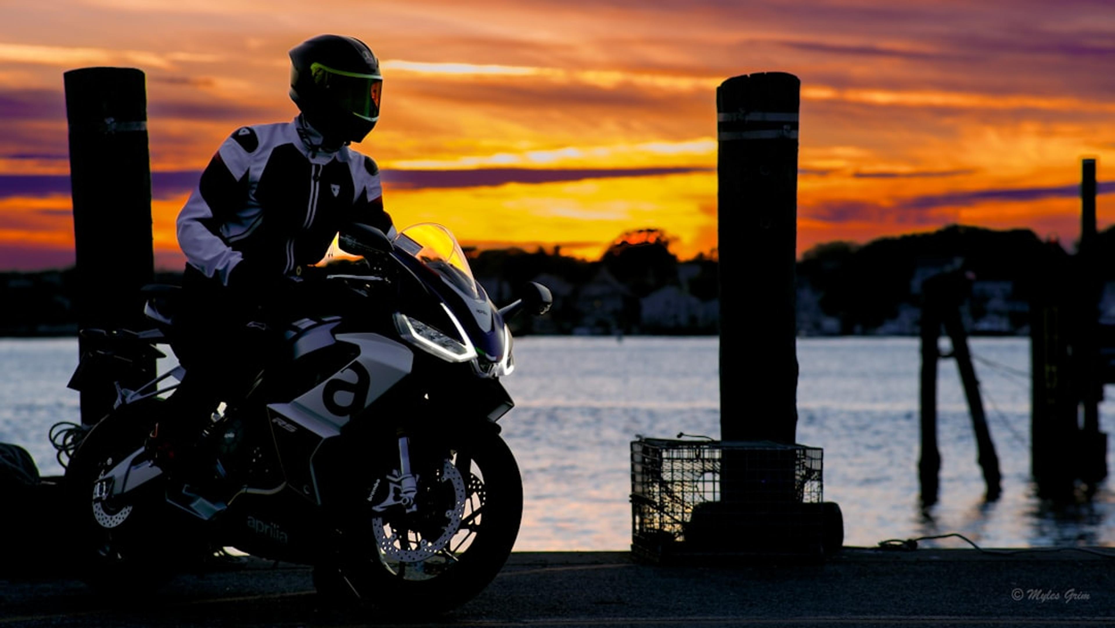 Motorcyclist on a bike at sunset near water