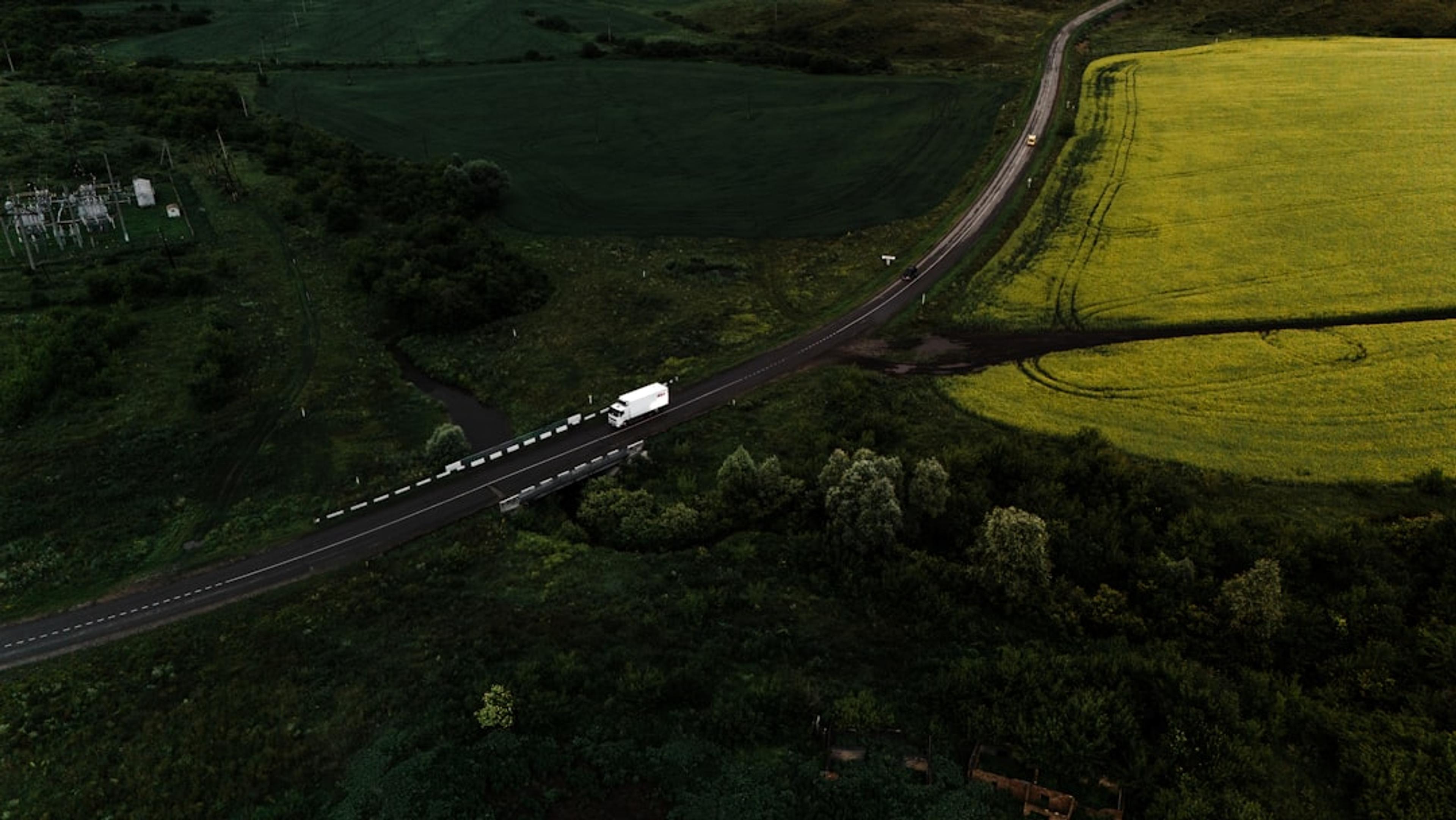 Truck driving on a road through green fields