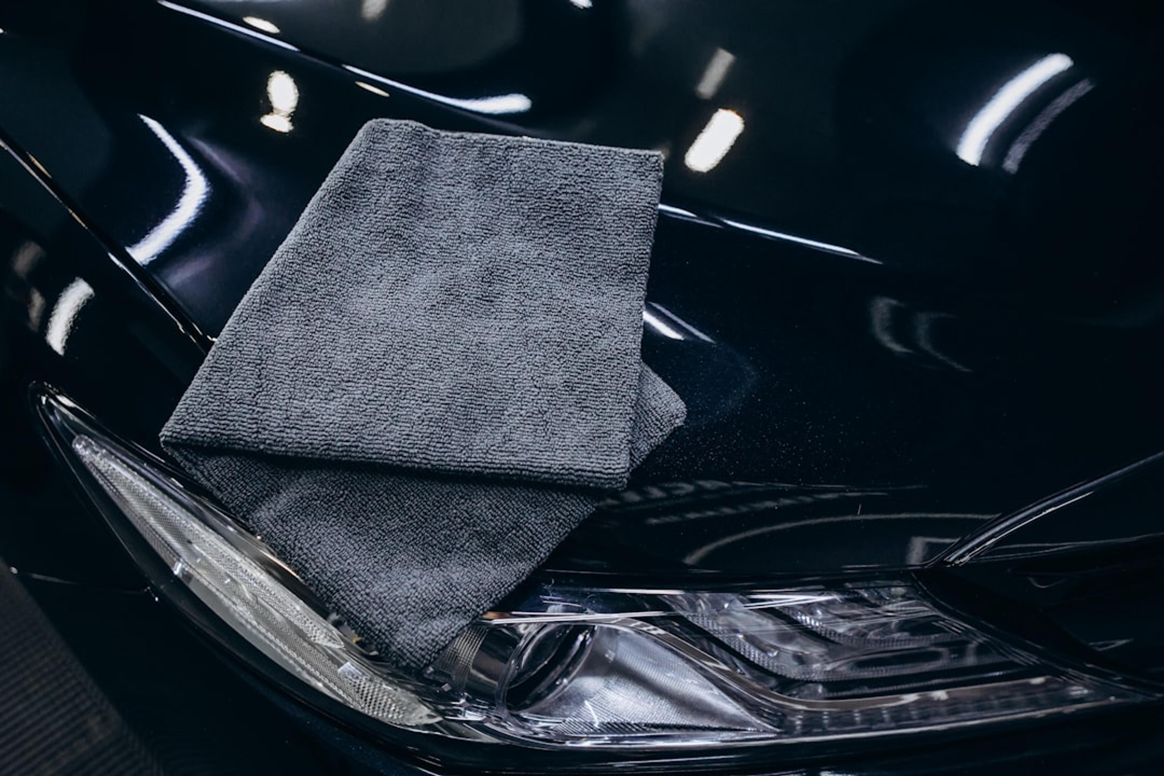 Gray microfiber cloth on a black car hood.