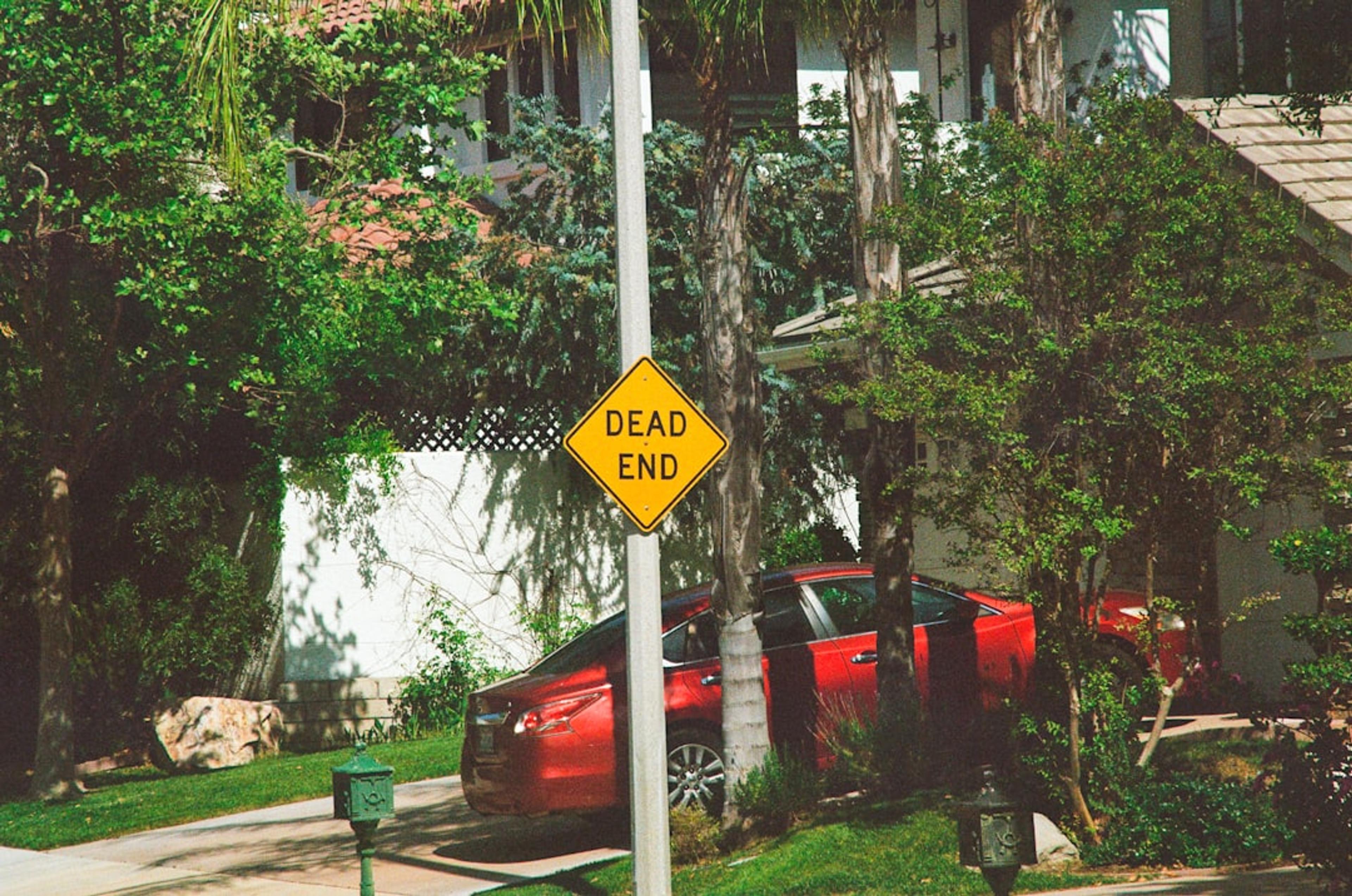 a yellow sign that says lead ends next to a red car