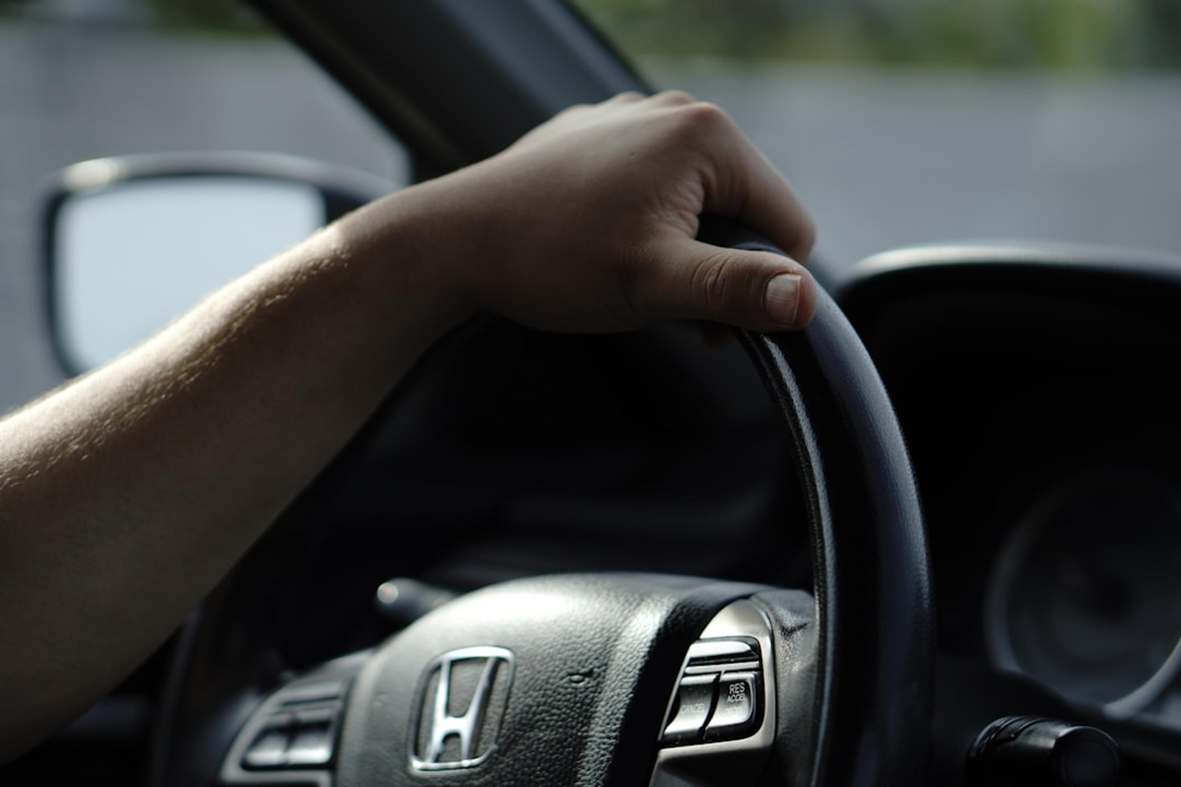 A hand grips the steering wheel.