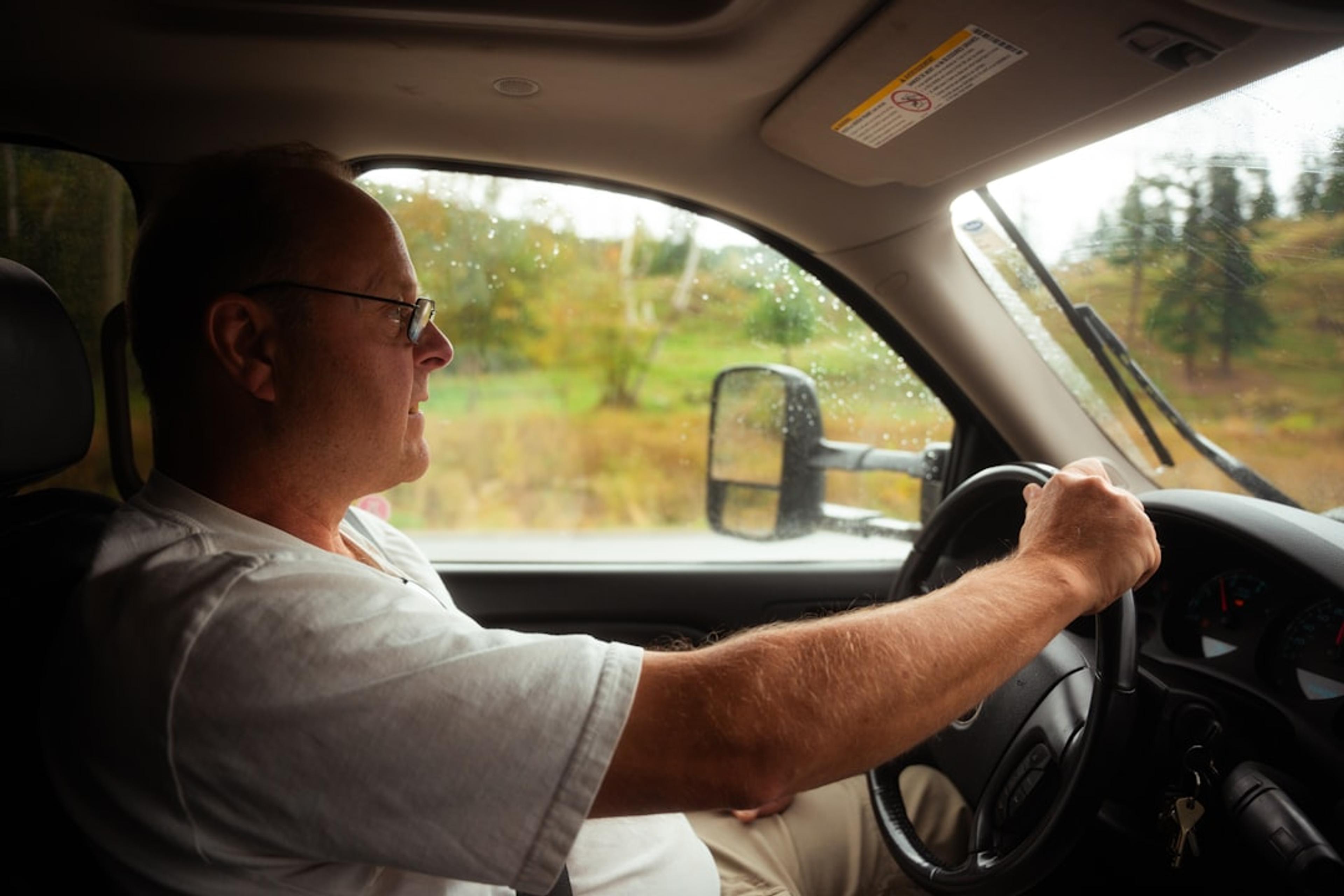 A man driving a car on a rural road