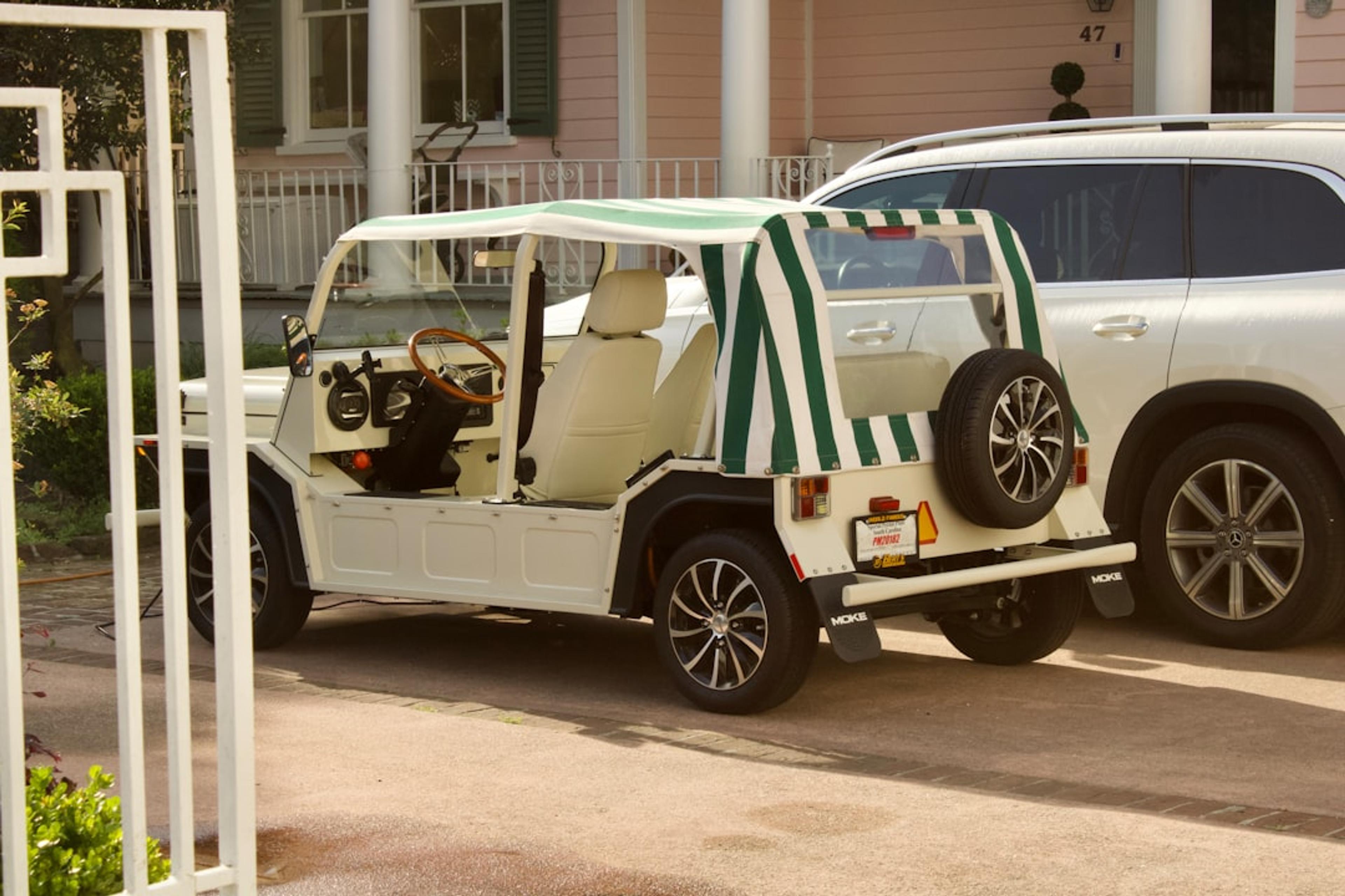 A white jeep parked in front of a pink house