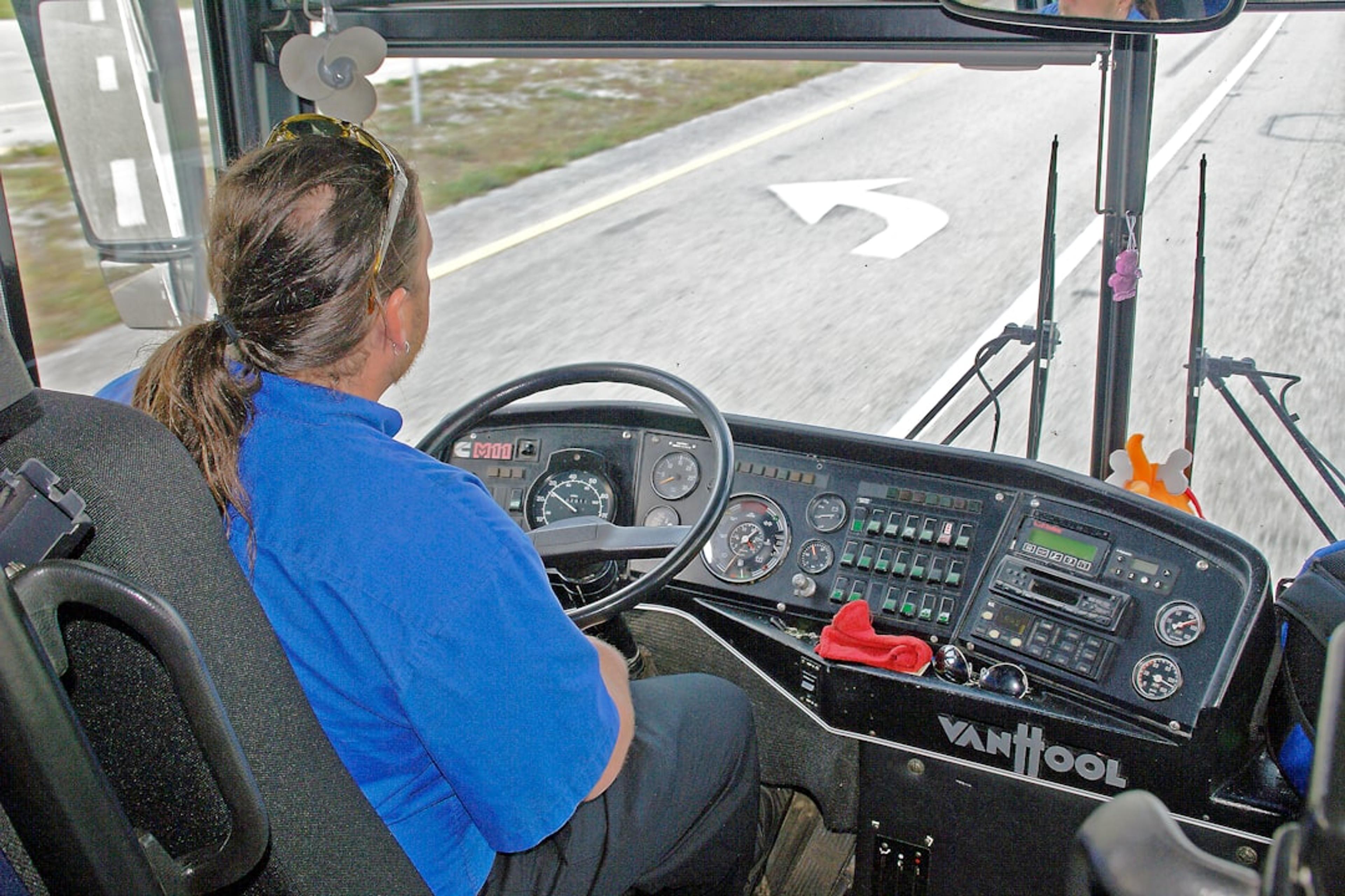 Driver in blue shirt operating a bus dashboard