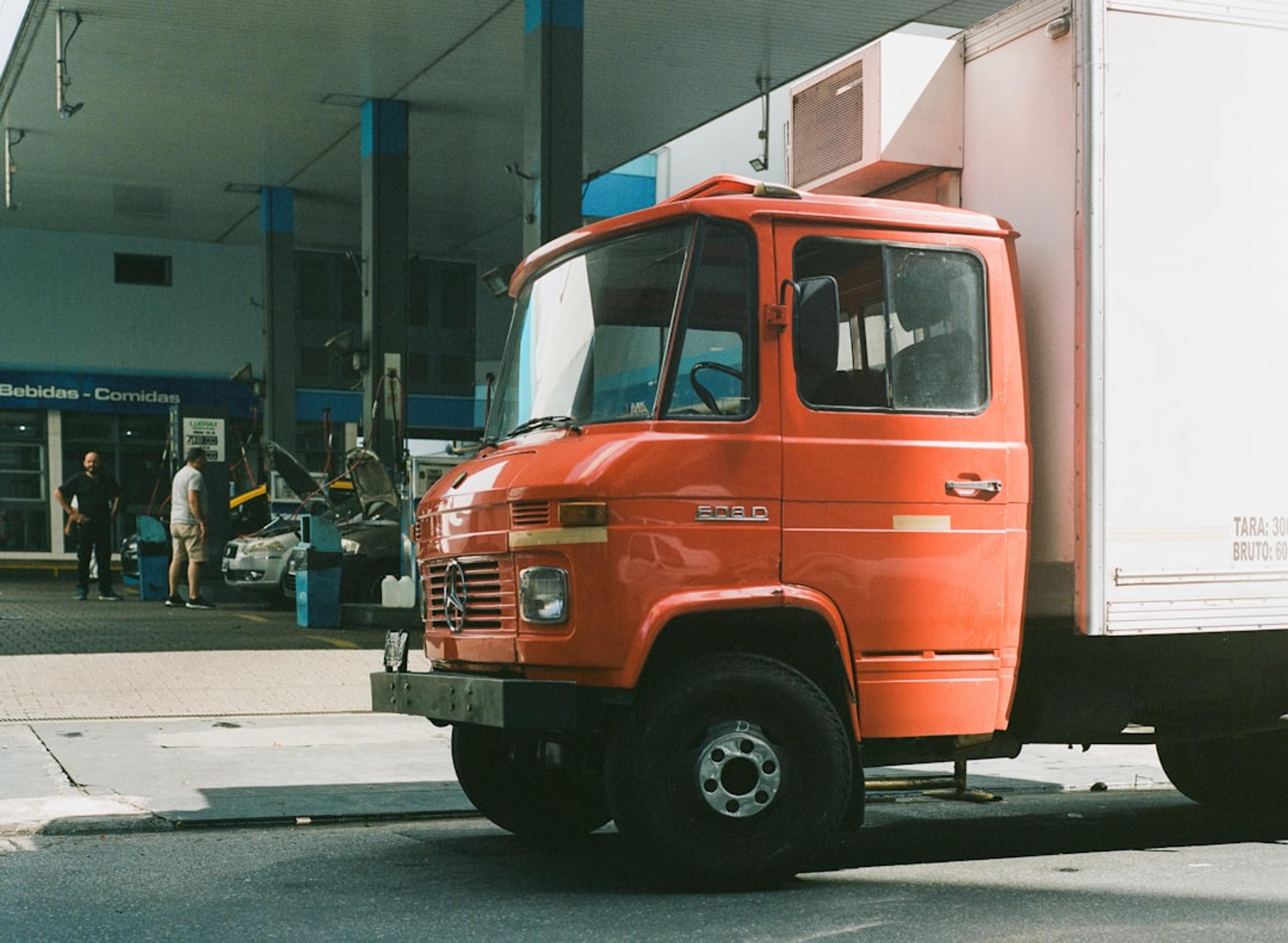 Orange truck parked at a gas station.