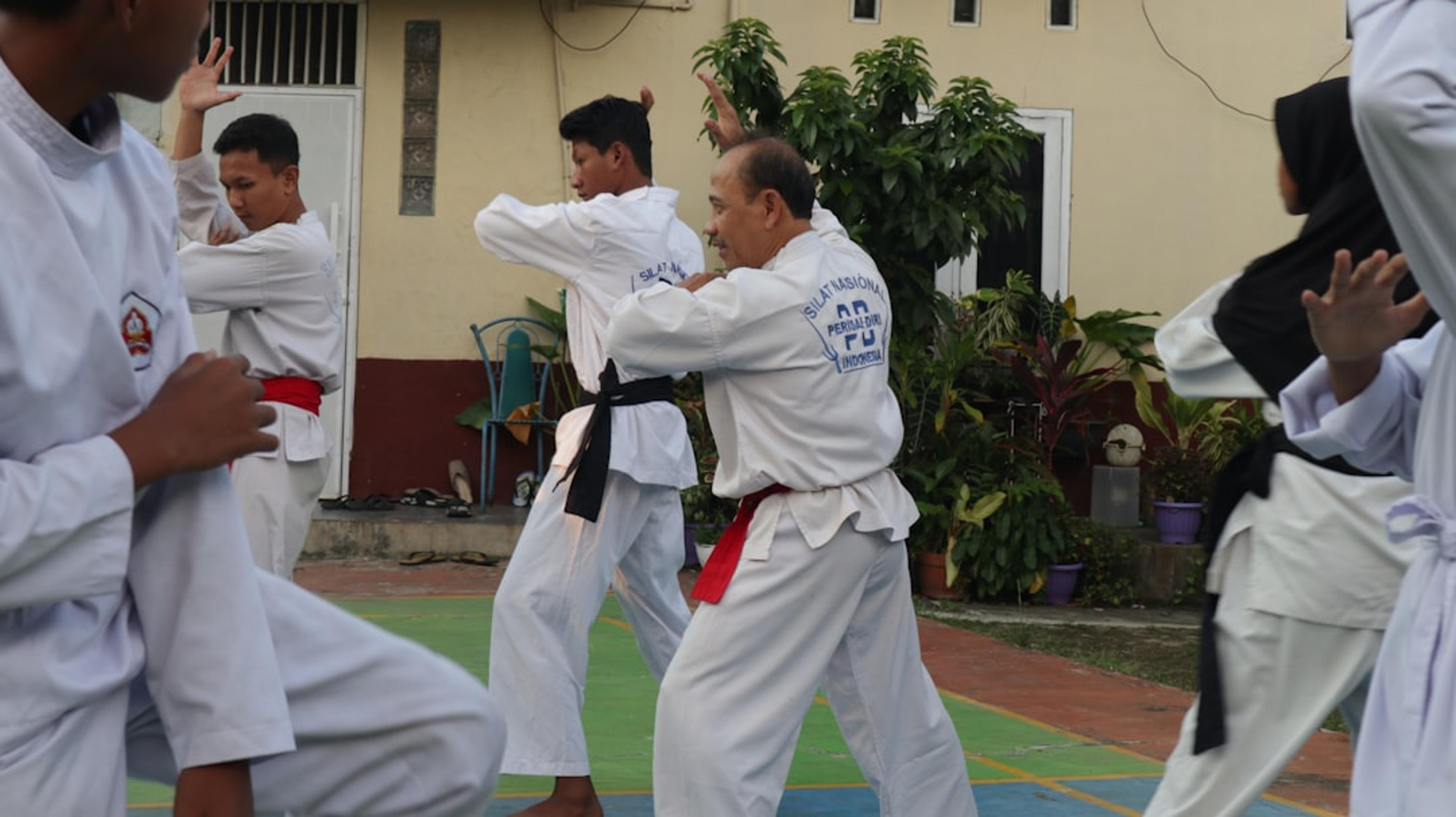 A group of men practicing karate in front of a building