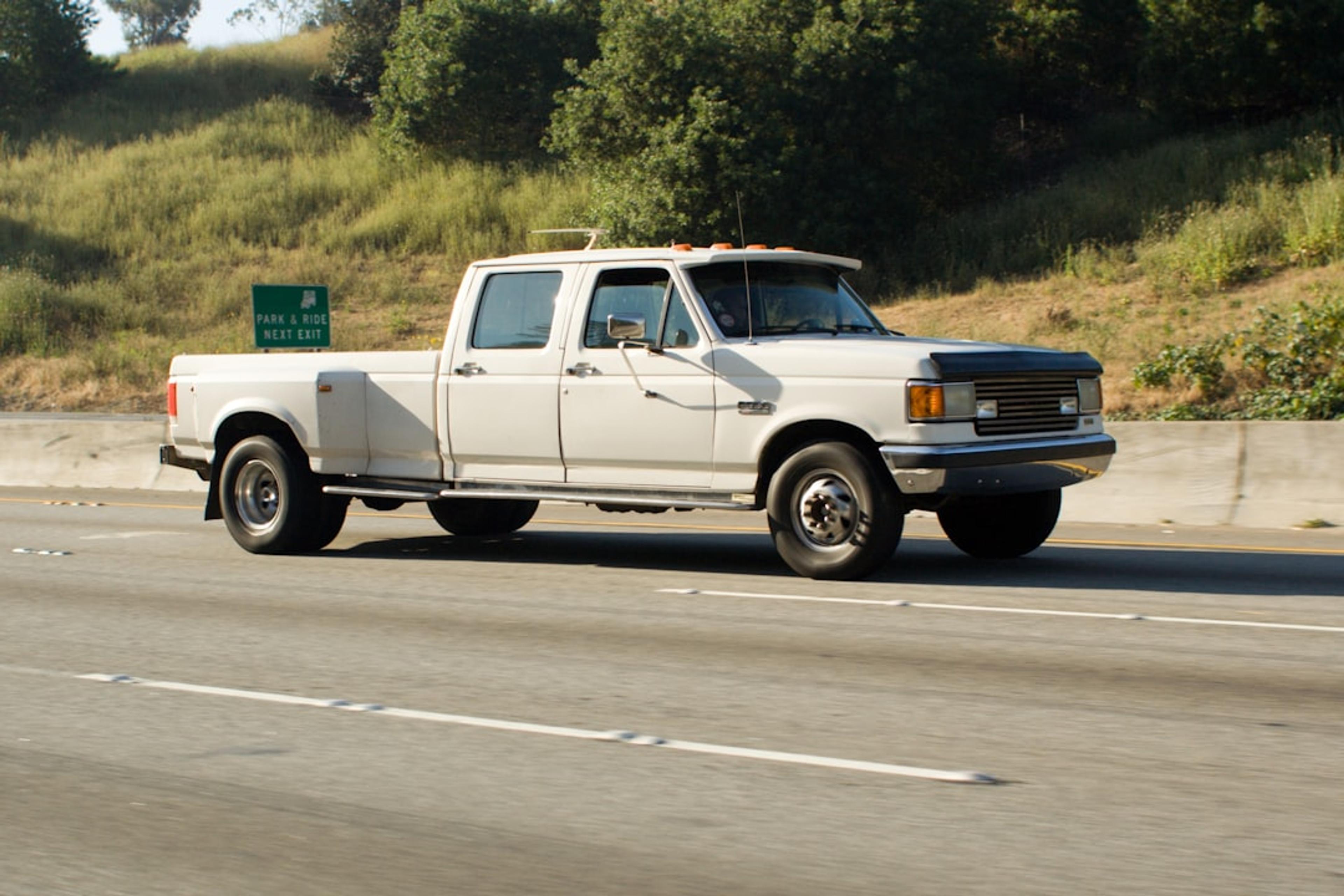 White pickup truck driving on a highway.