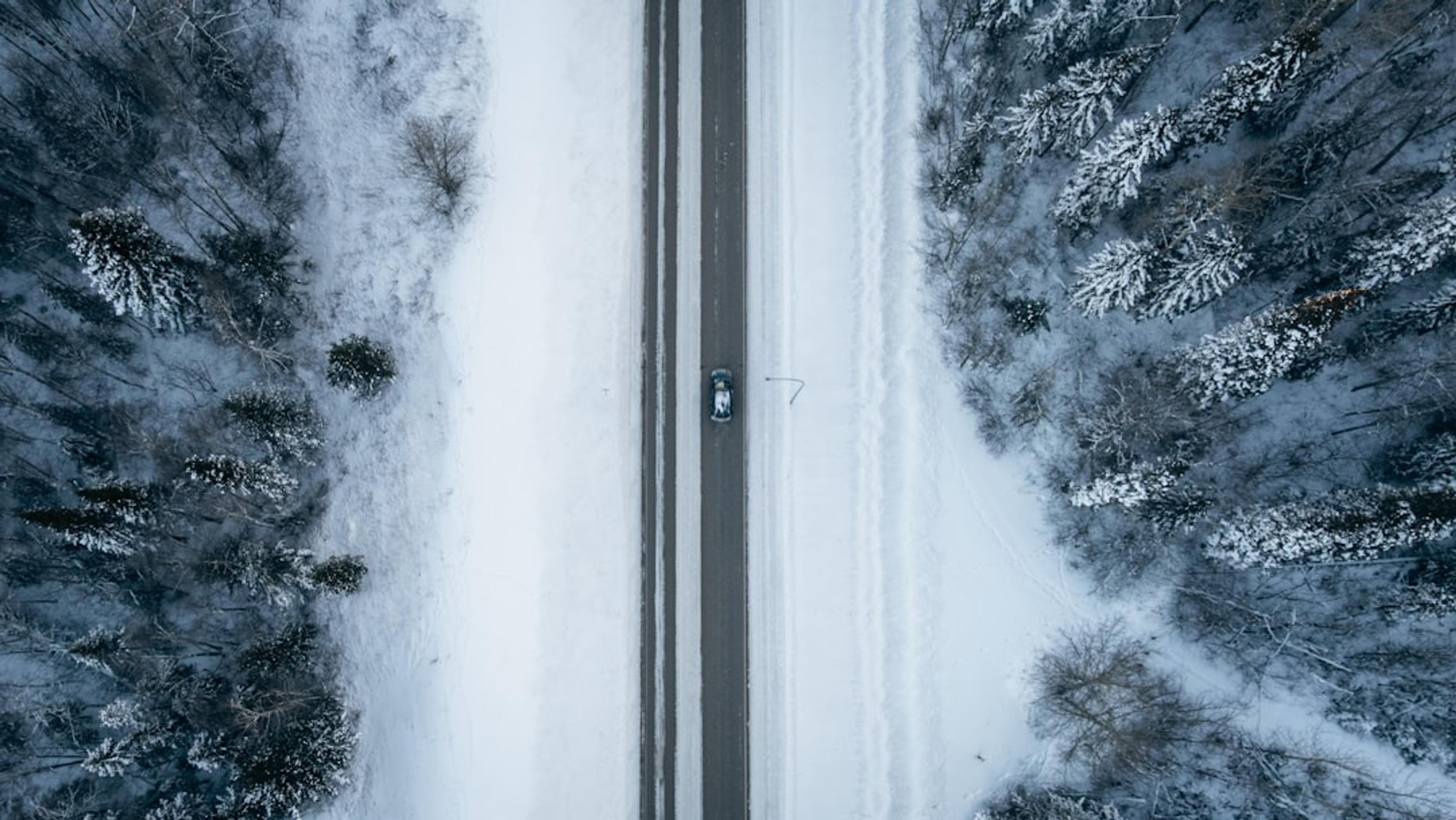 an aerial view of a road in the middle of a snowy forest