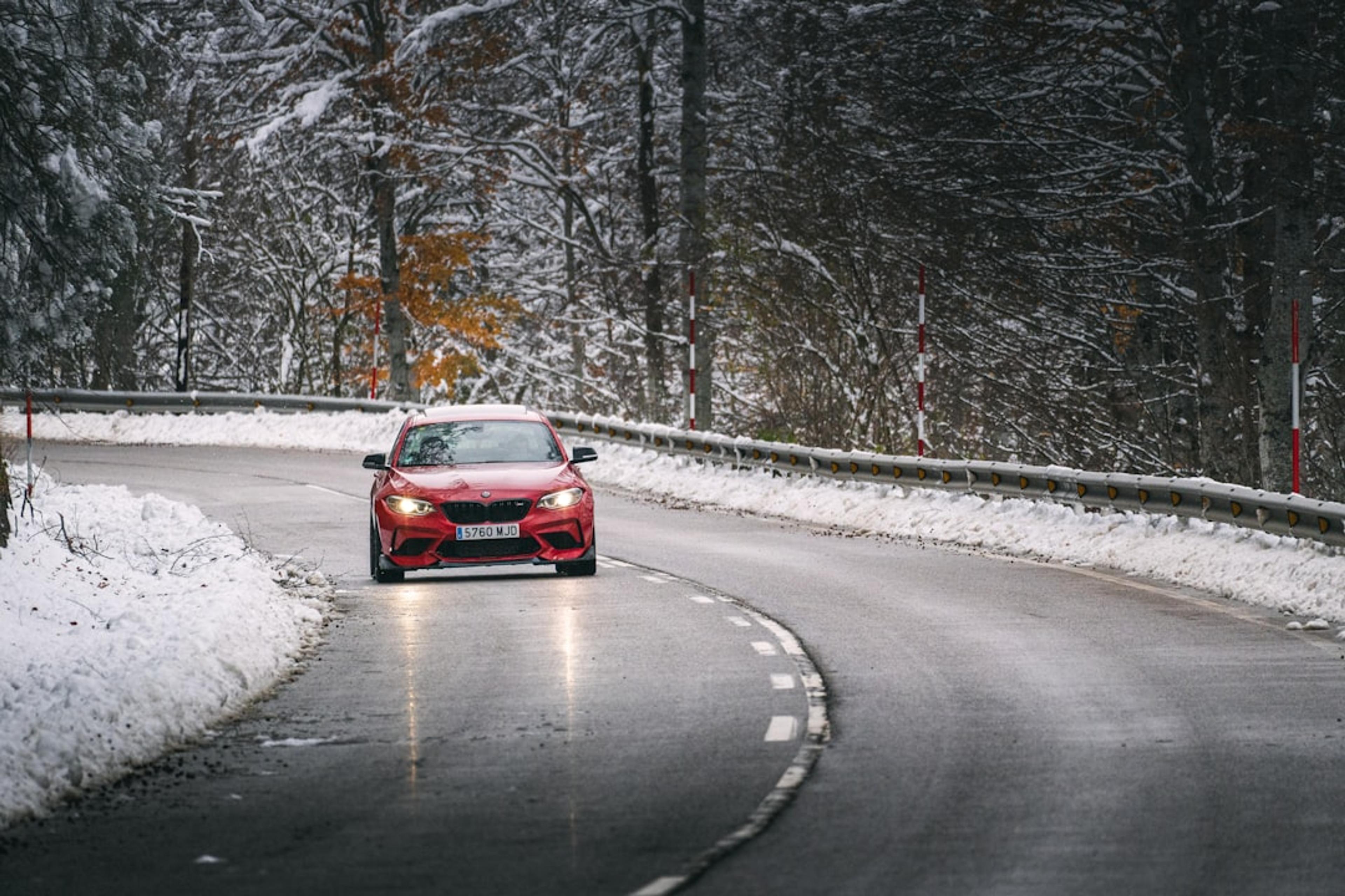 Red car driving on a wet, snowy road