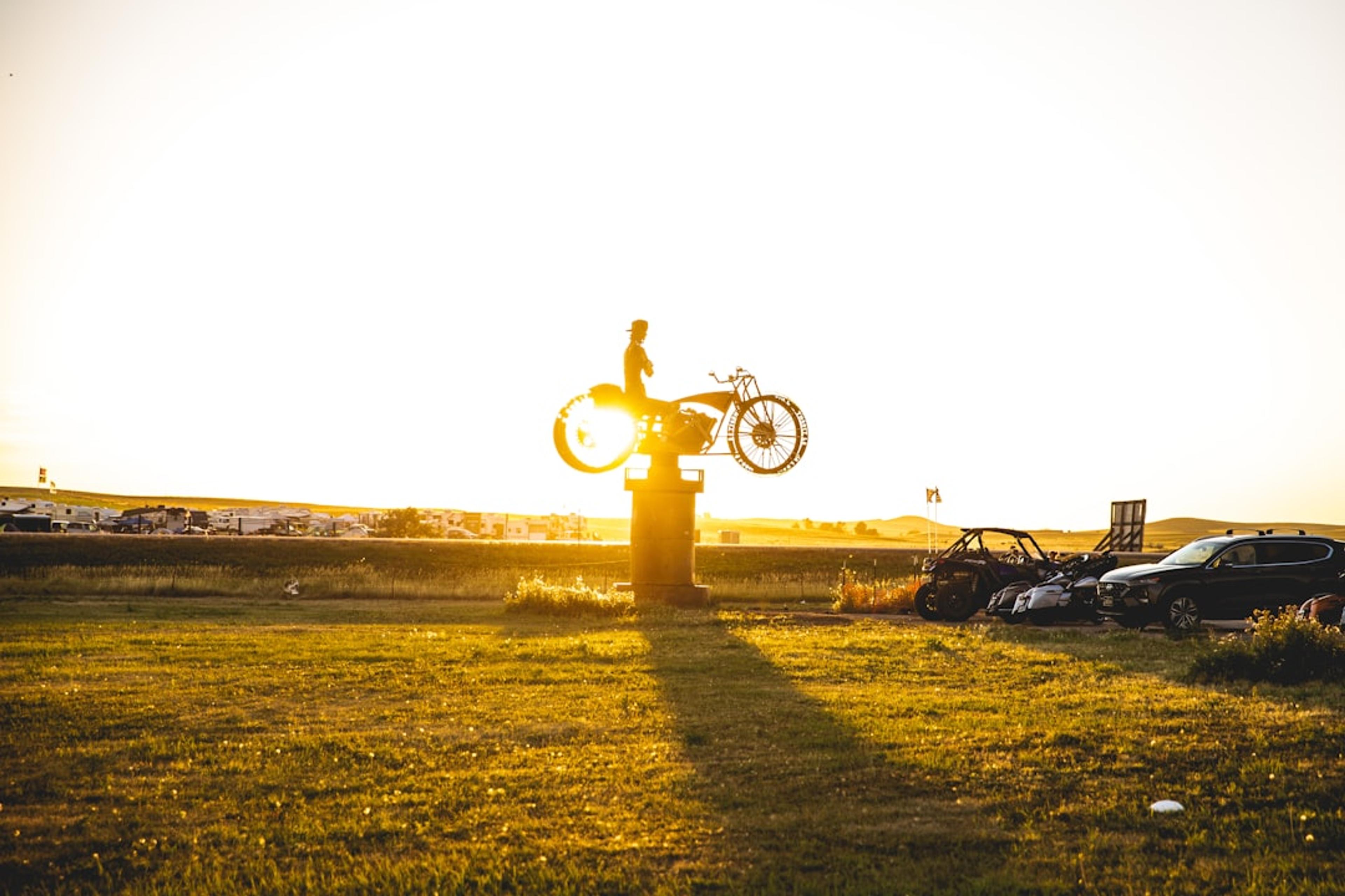 A person balances a bike in the sunset.