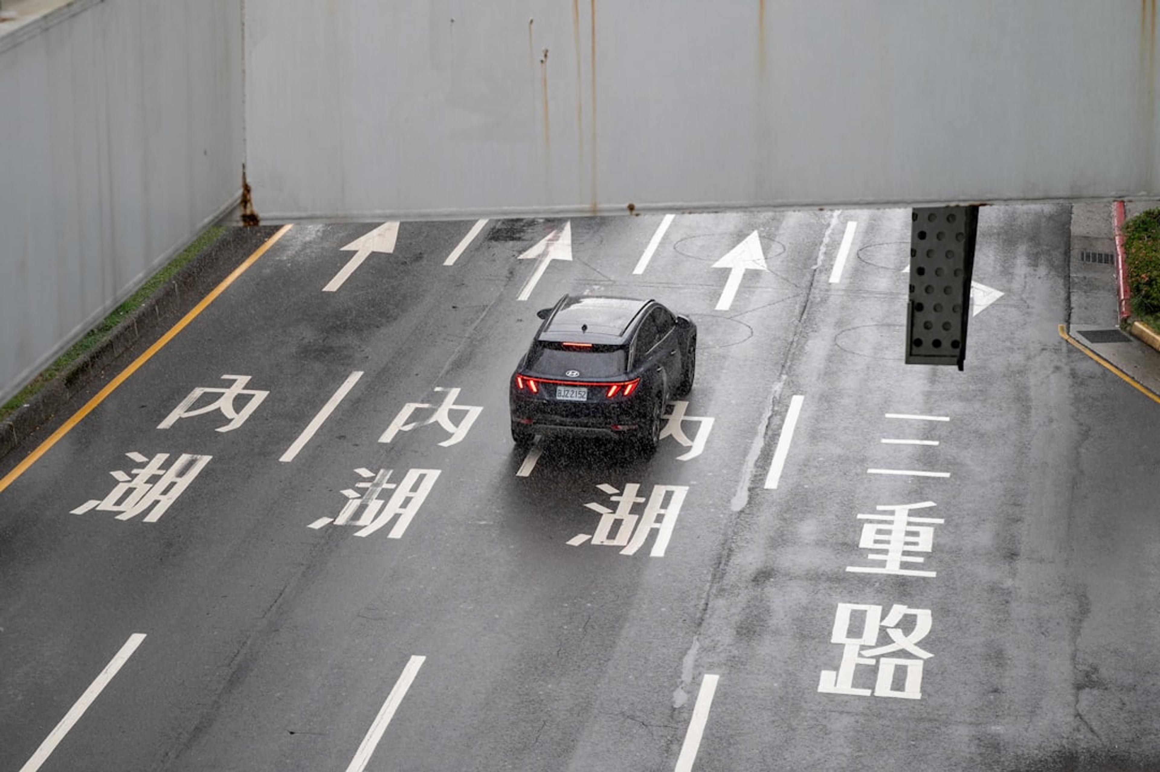 Car driving on wet road with chinese characters.