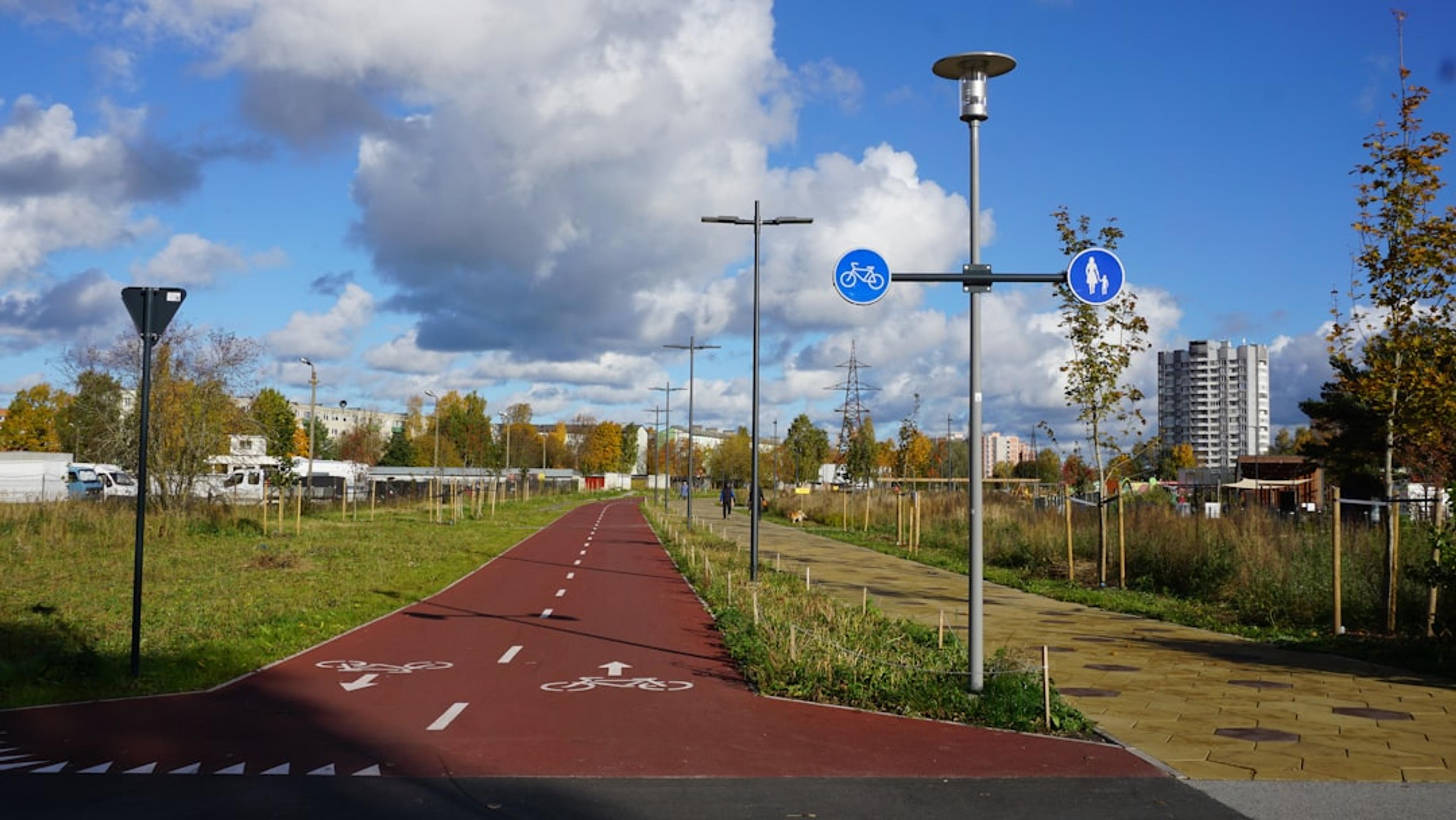 Red bike path with signs in grassy park