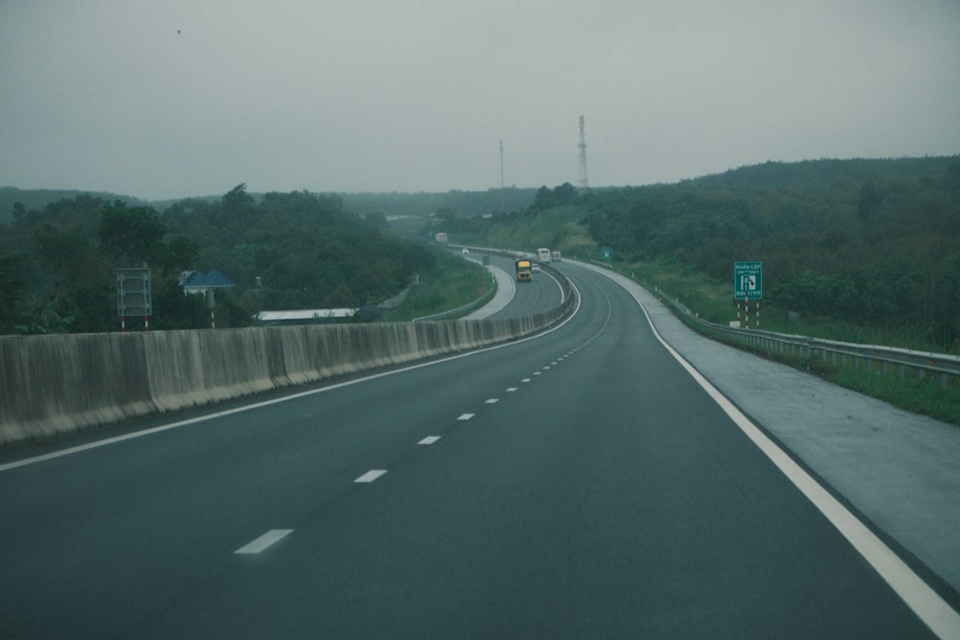 Highway curving through green hills under a cloudy sky