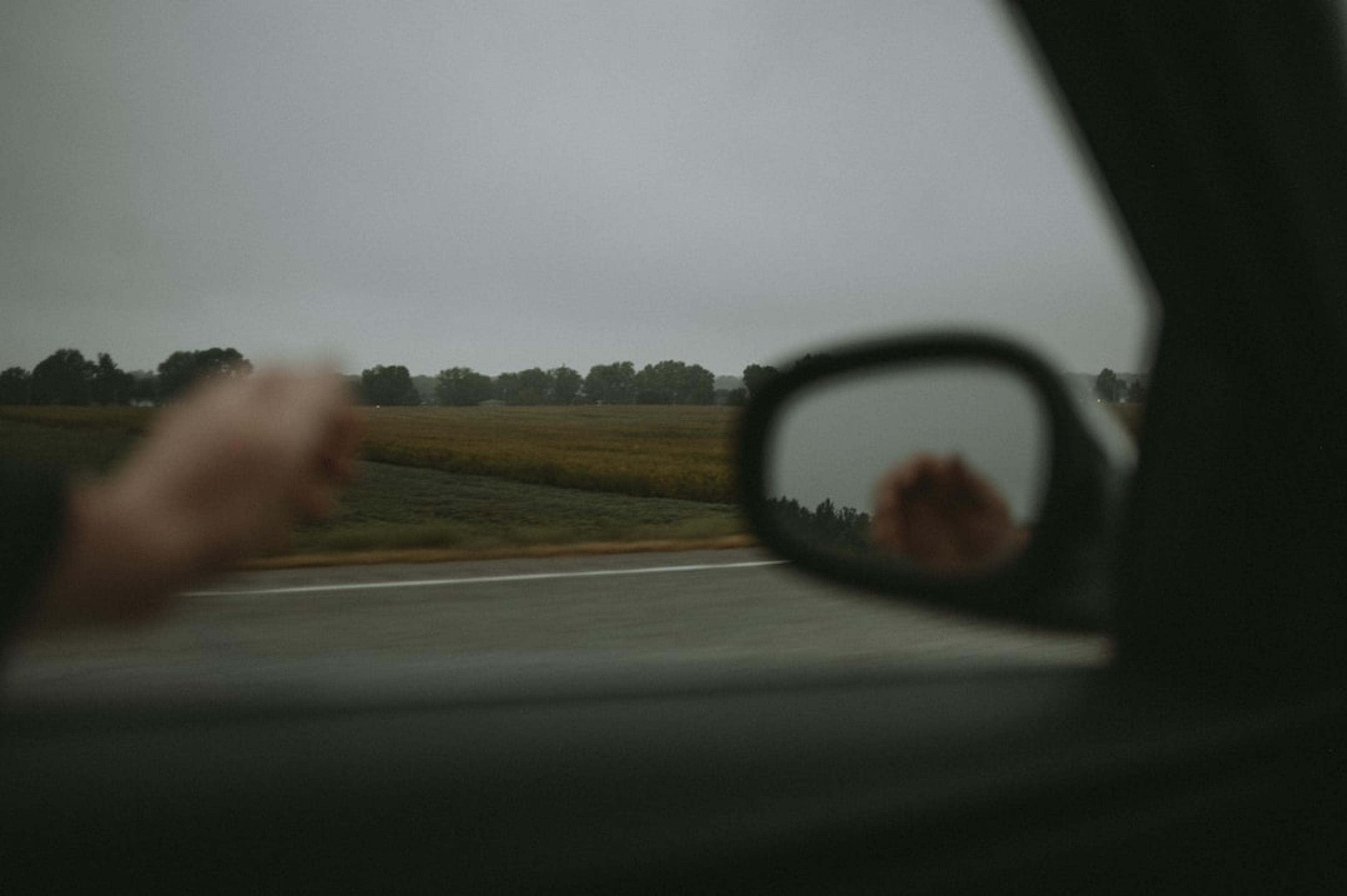 a person's reflection in the side view mirror of a car