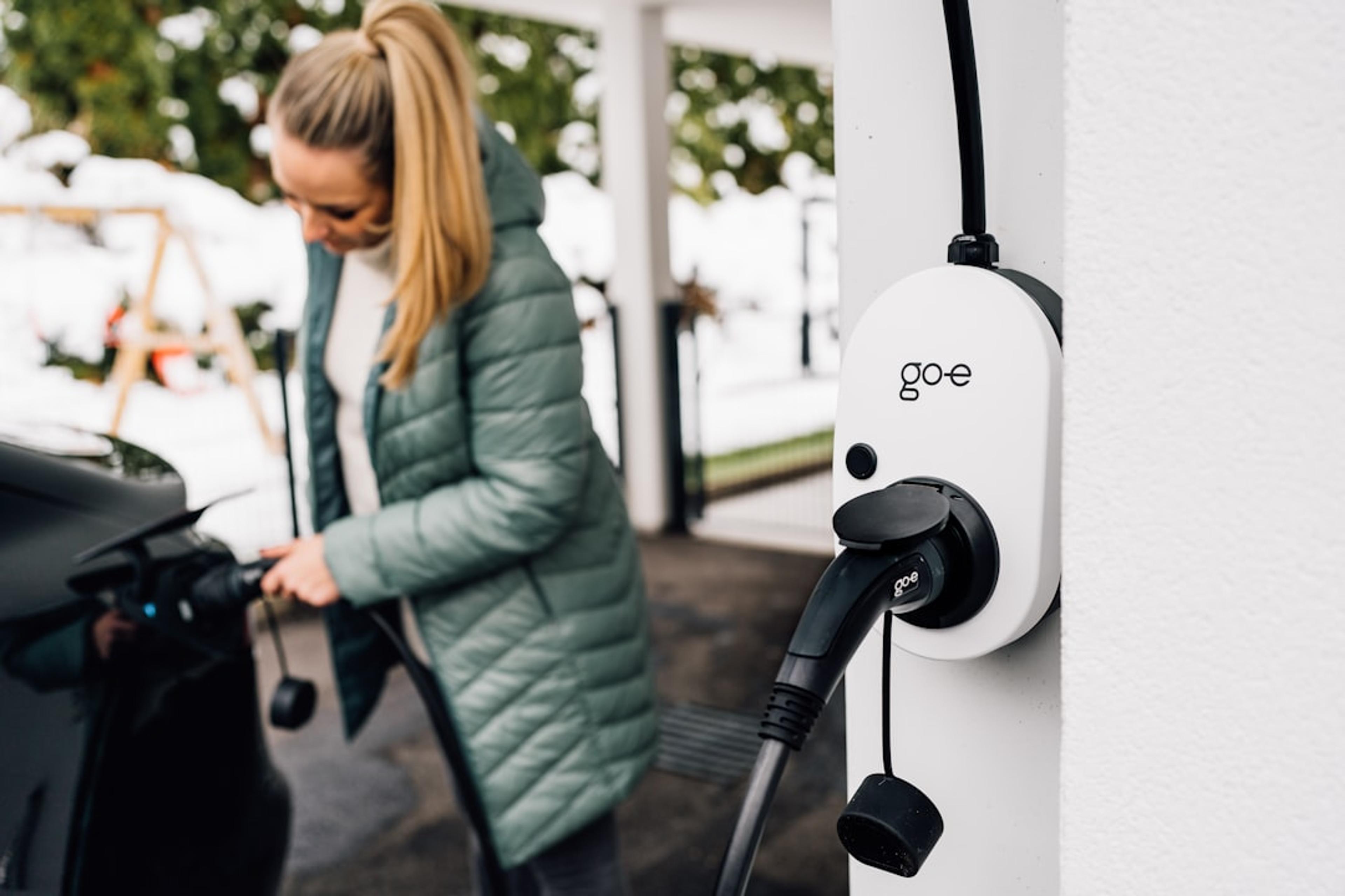 Woman plugs in an electric car to charge.