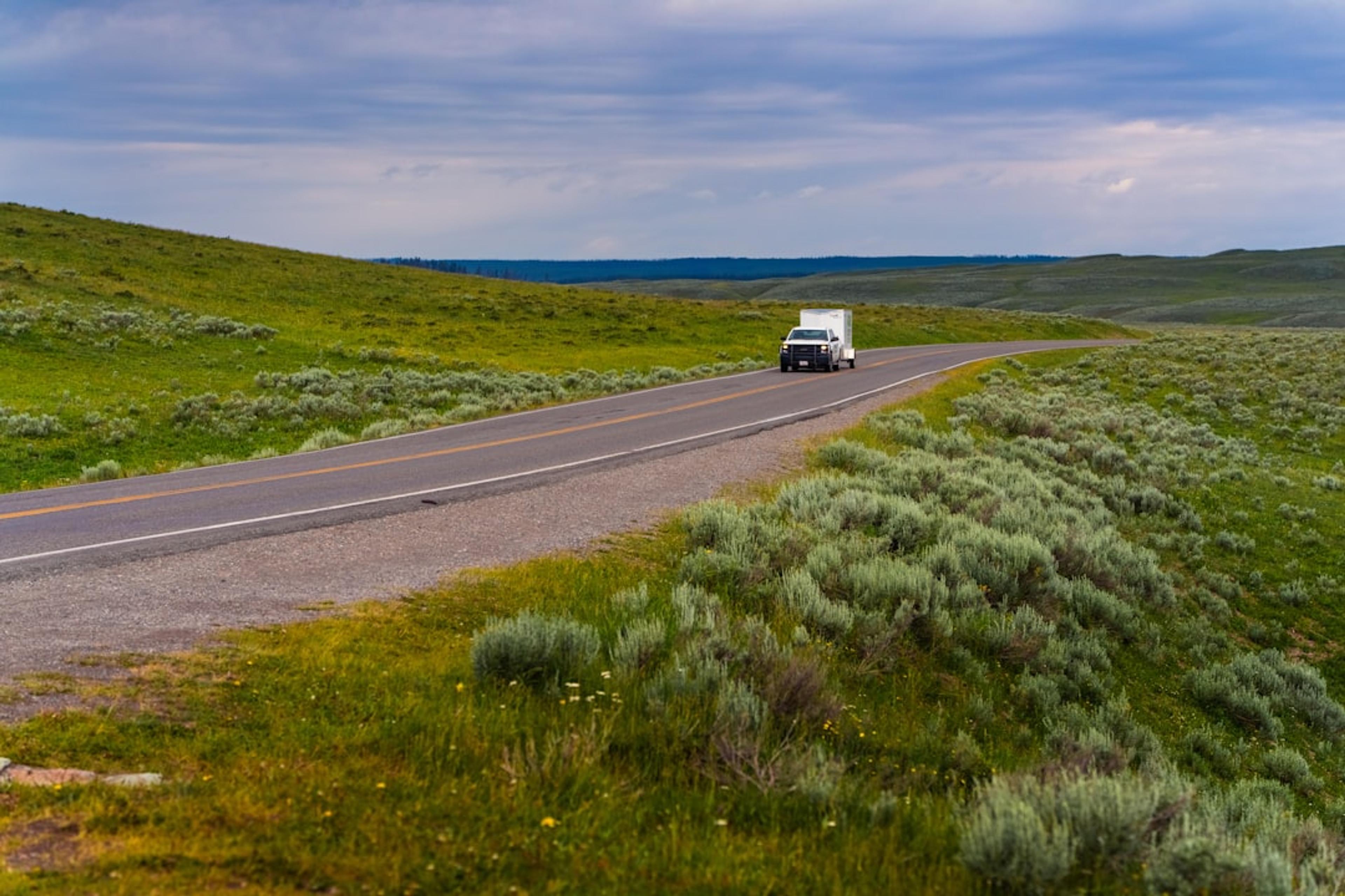Rv travels down a winding road through green hills