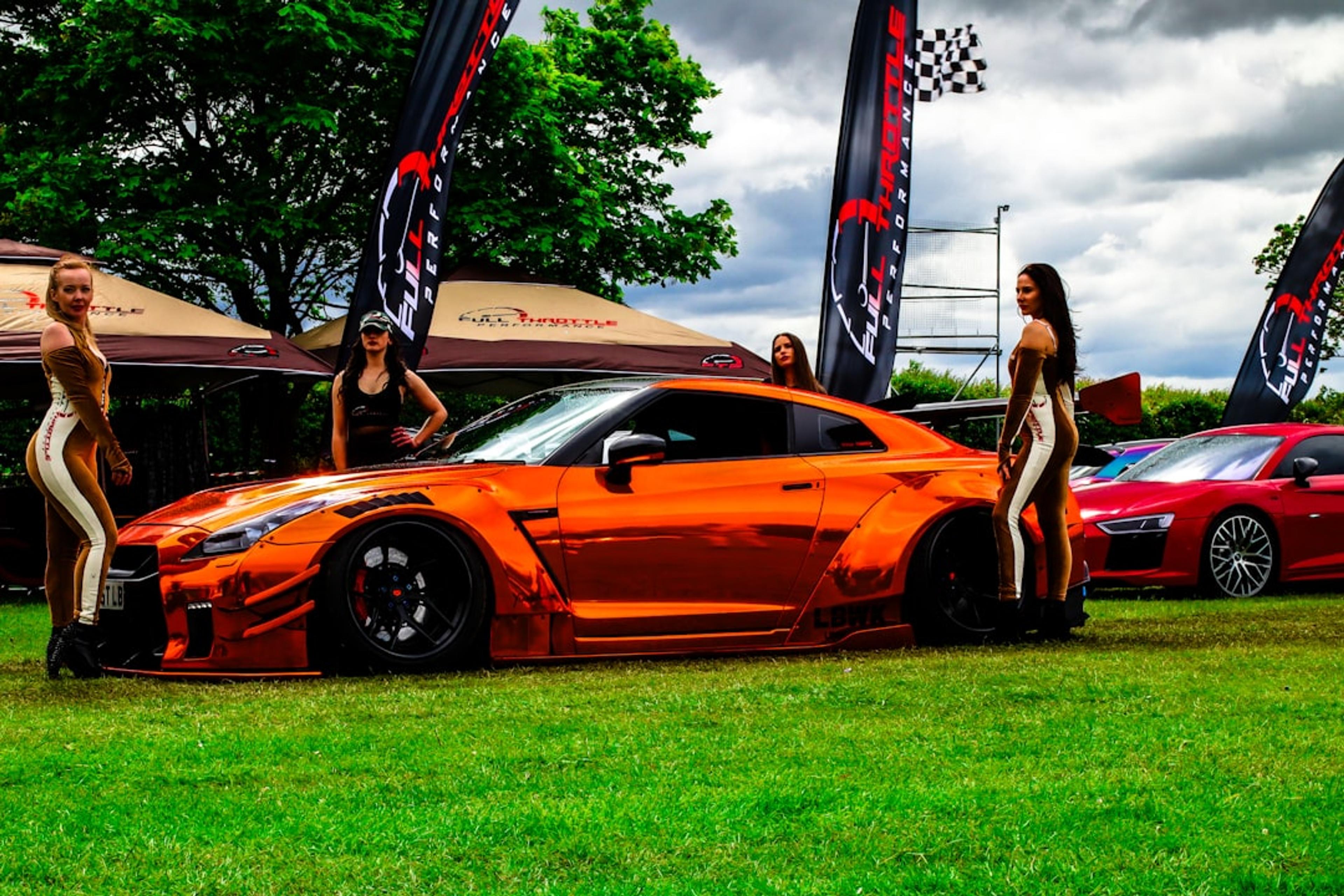 A group of women standing next to a sports car