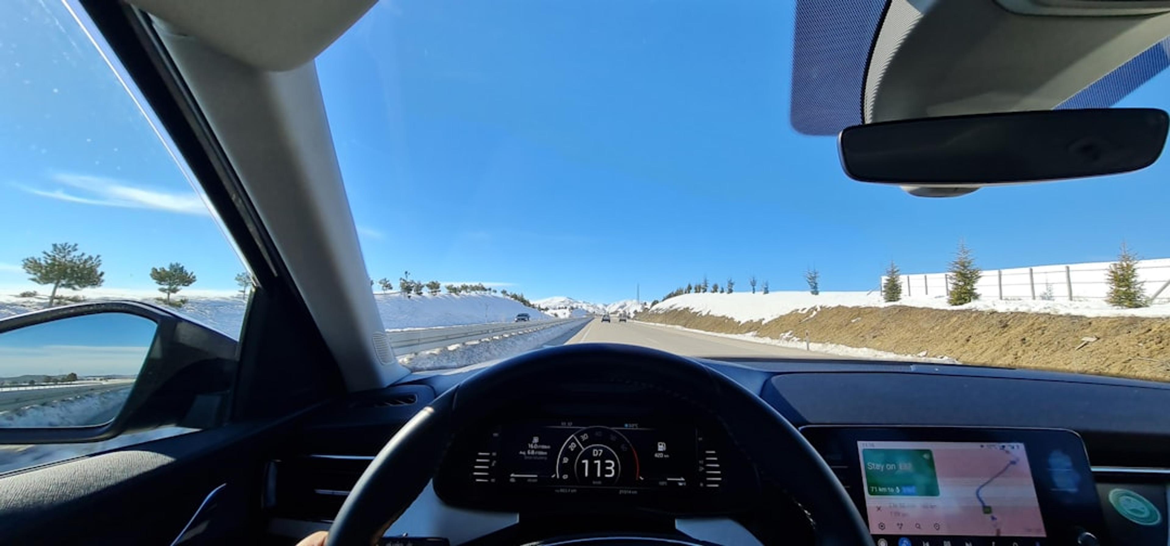 a car driving down a road next to a snow covered hillside