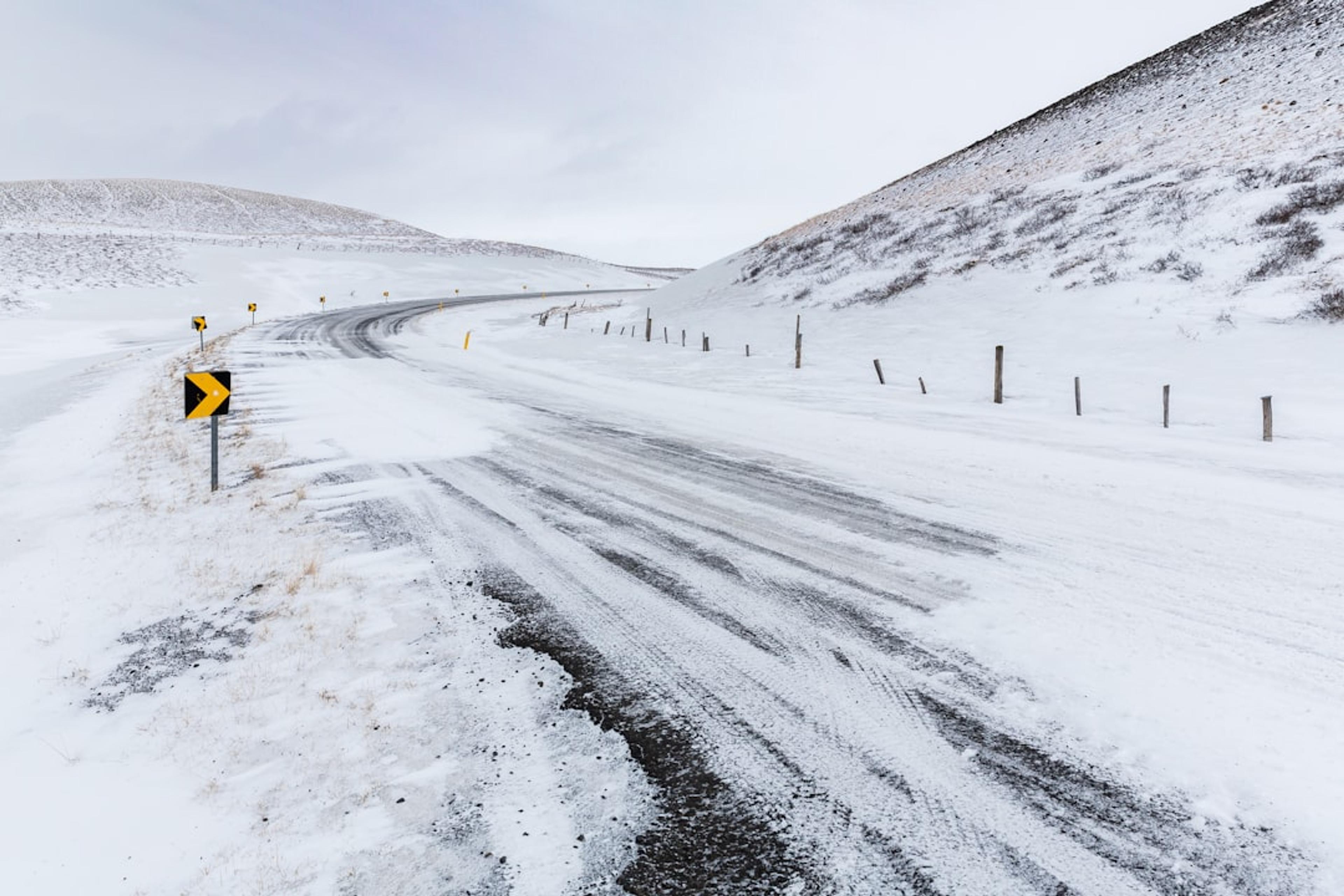 A snow-covered road winds through a barren landscape.