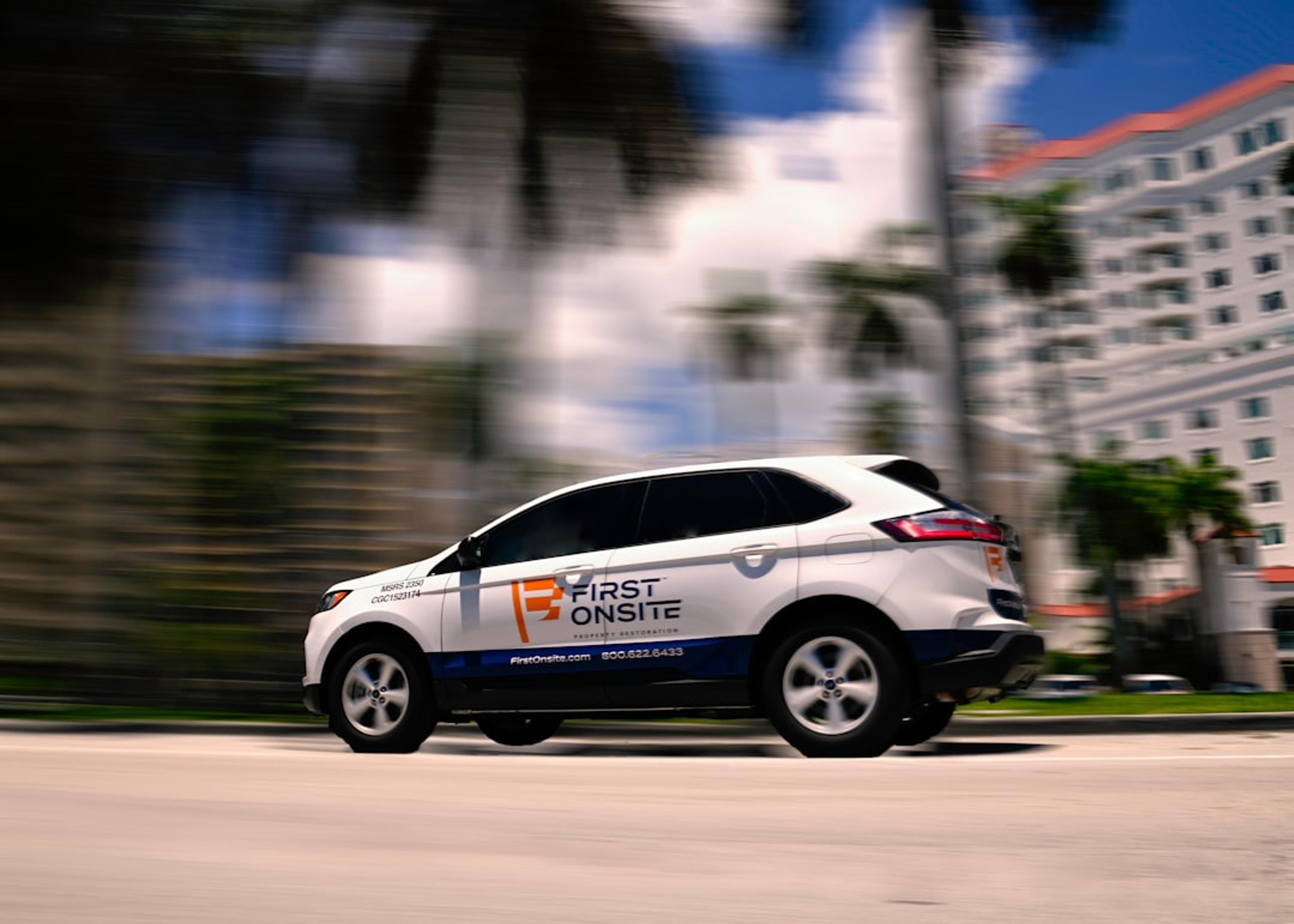 a white car driving down a street next to tall buildings