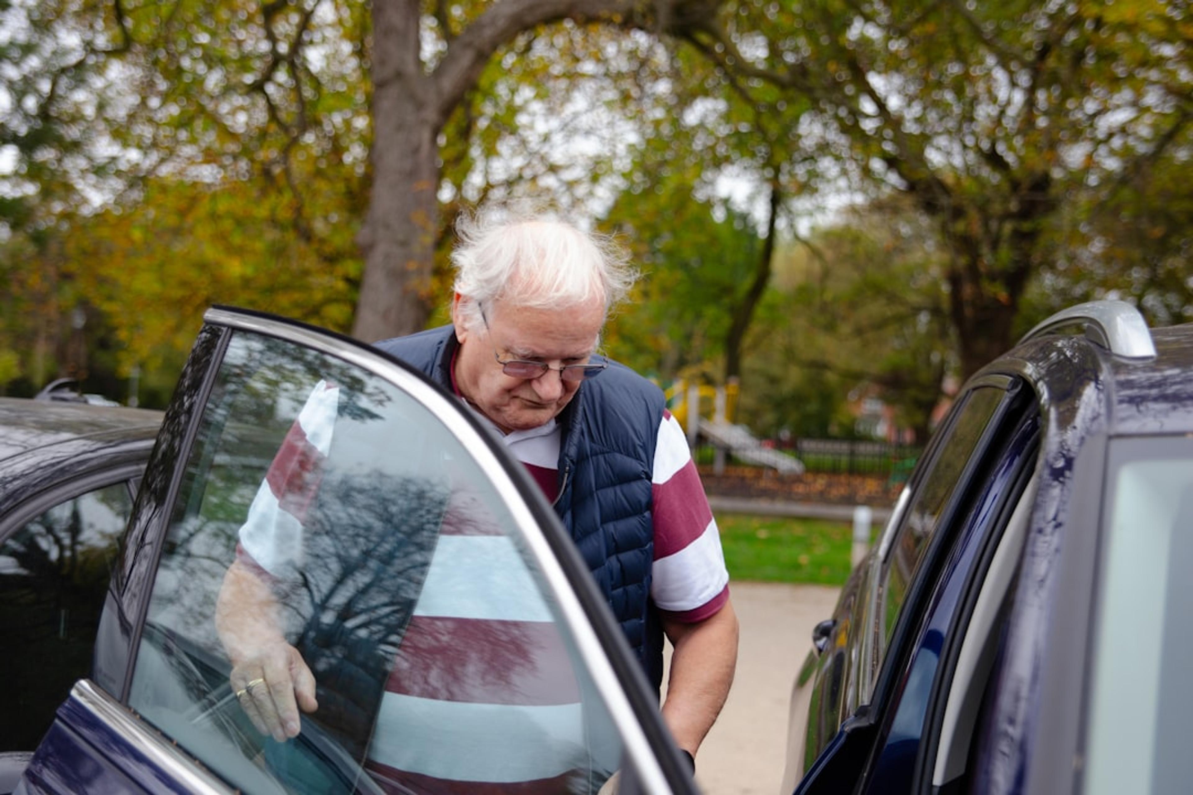 Elderly man getting into a car